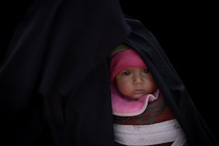 A baby girl is half visible through a swaddle.