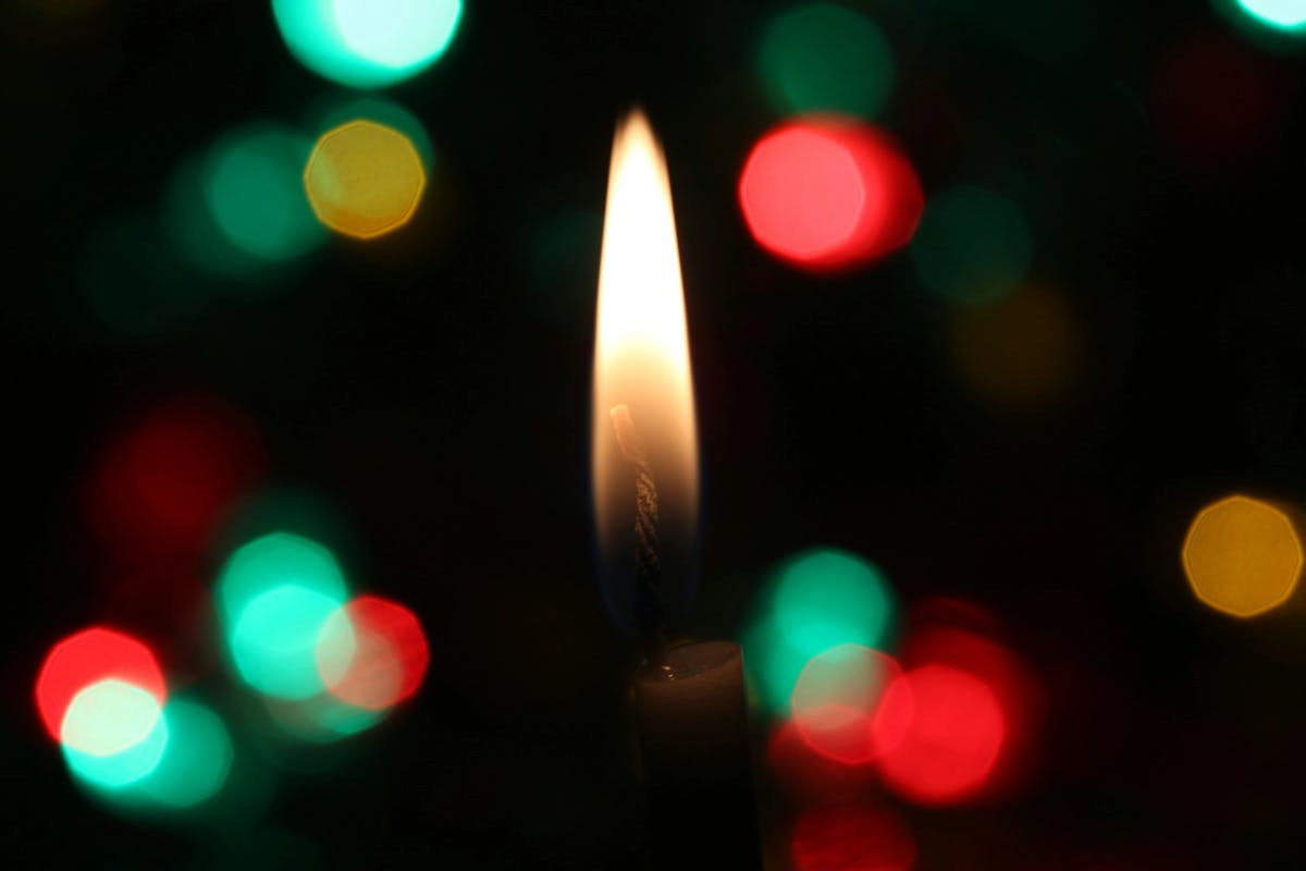 Close up of a candle light with holiday lights