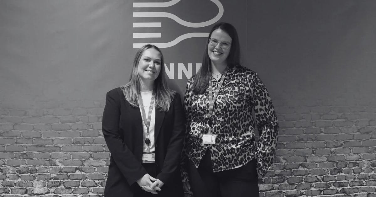 Black and white image of two women standing in front of the Innnes logo.