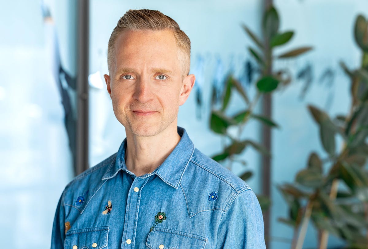 Portrait of middle aged man with a denim shirt and plants in the background