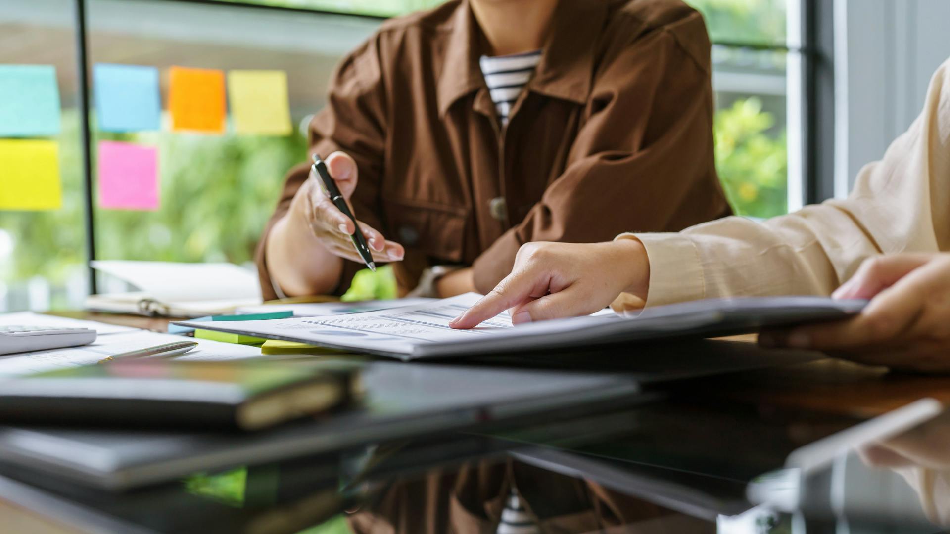 Two seated colleagues in their office discussing a document in front of them