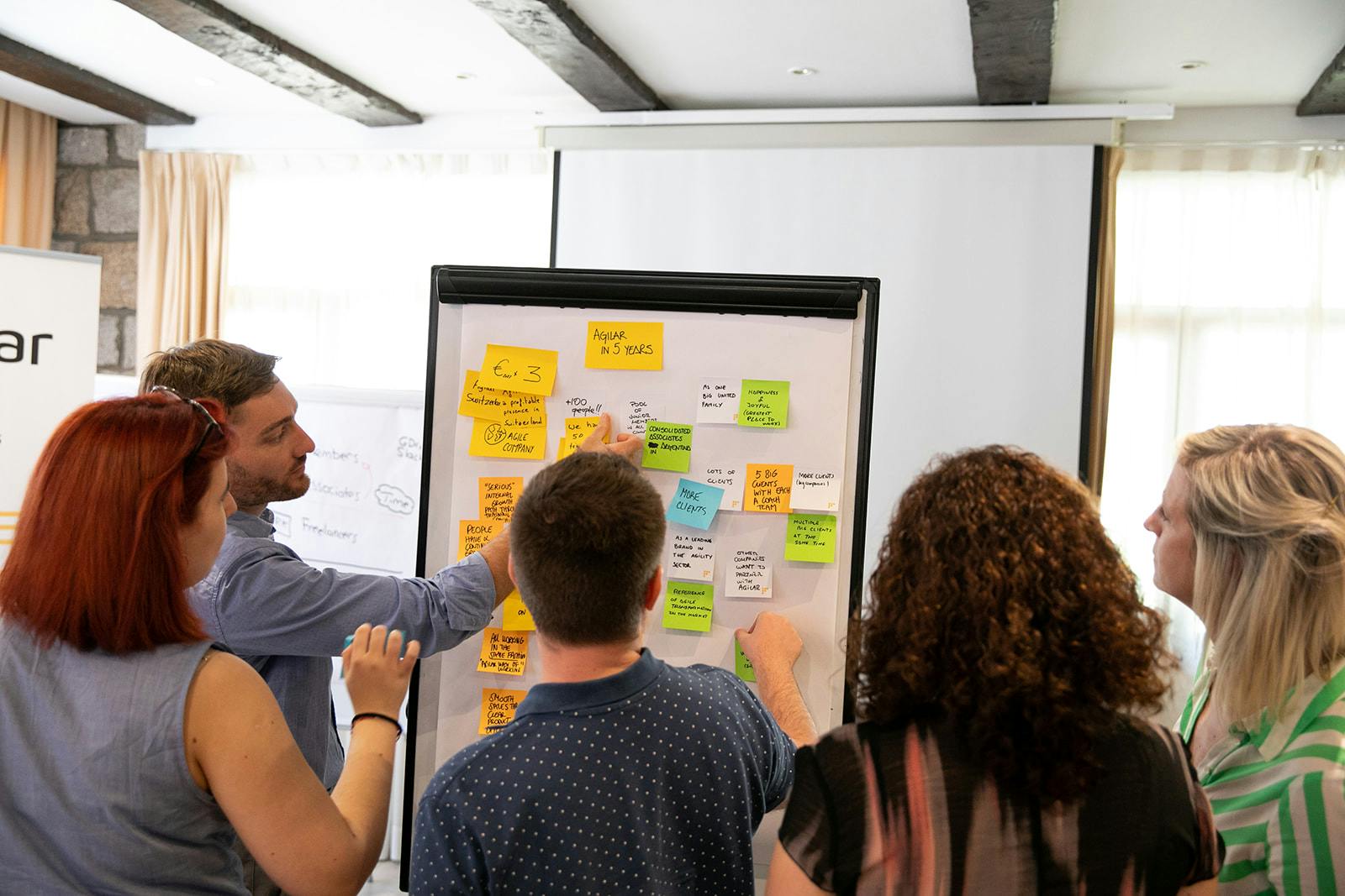 Un equipo trabajando junto frente a un tablero con post-its.