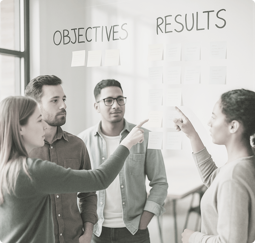 Team collaborating on OKRs with sticky notes on a glass board