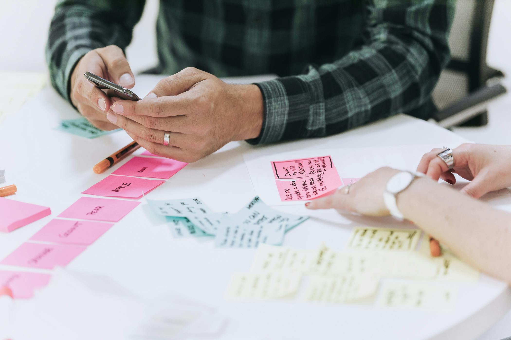 A co-worker checking his phone on atable full of post-its