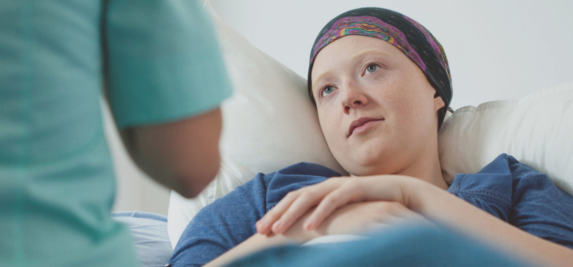 A cancer patient resting in a bed while having a conversation with a healthcare provider