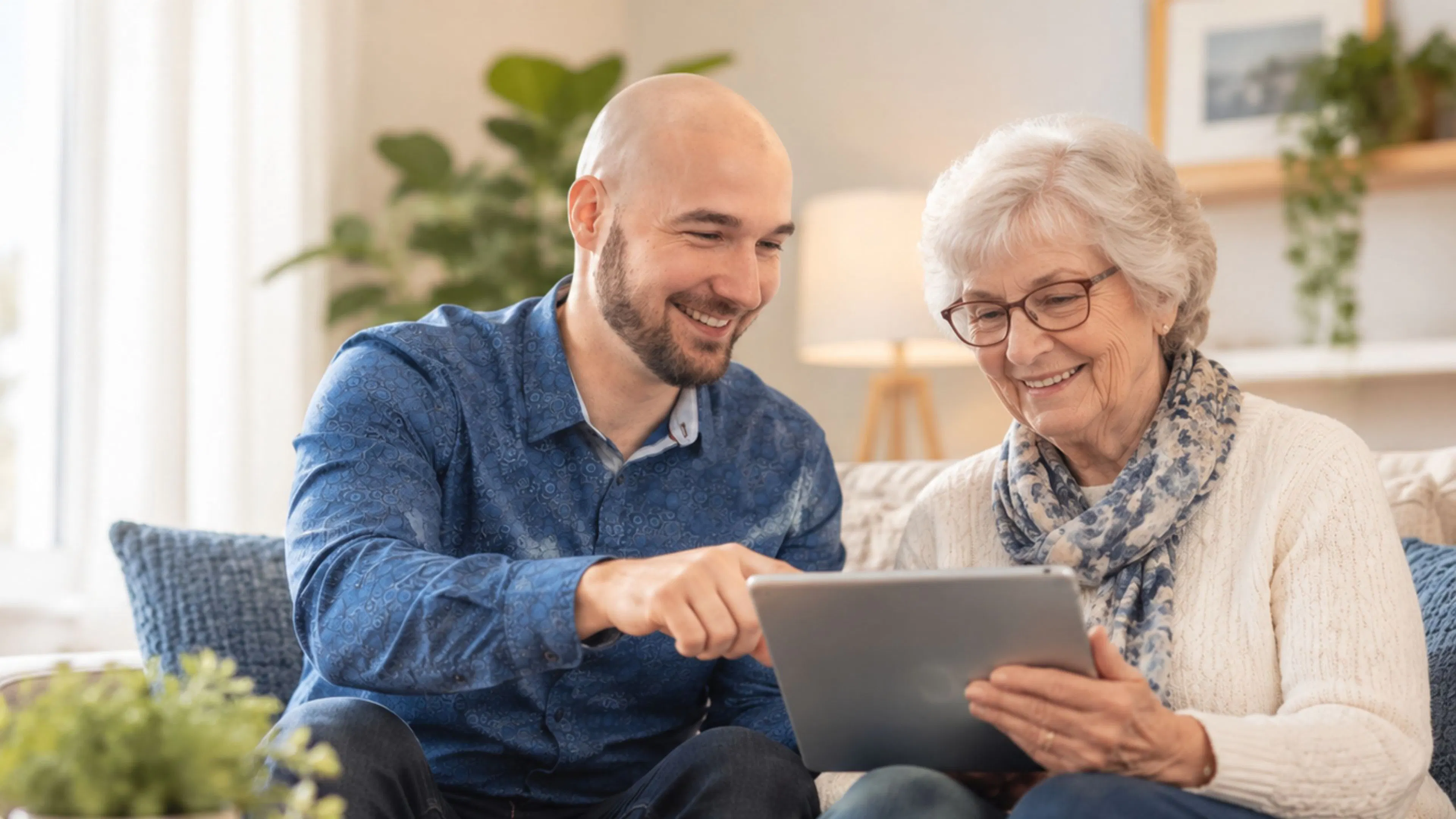 Un aidant aide une personne âgée à utiliser sa nouvelle tablette.