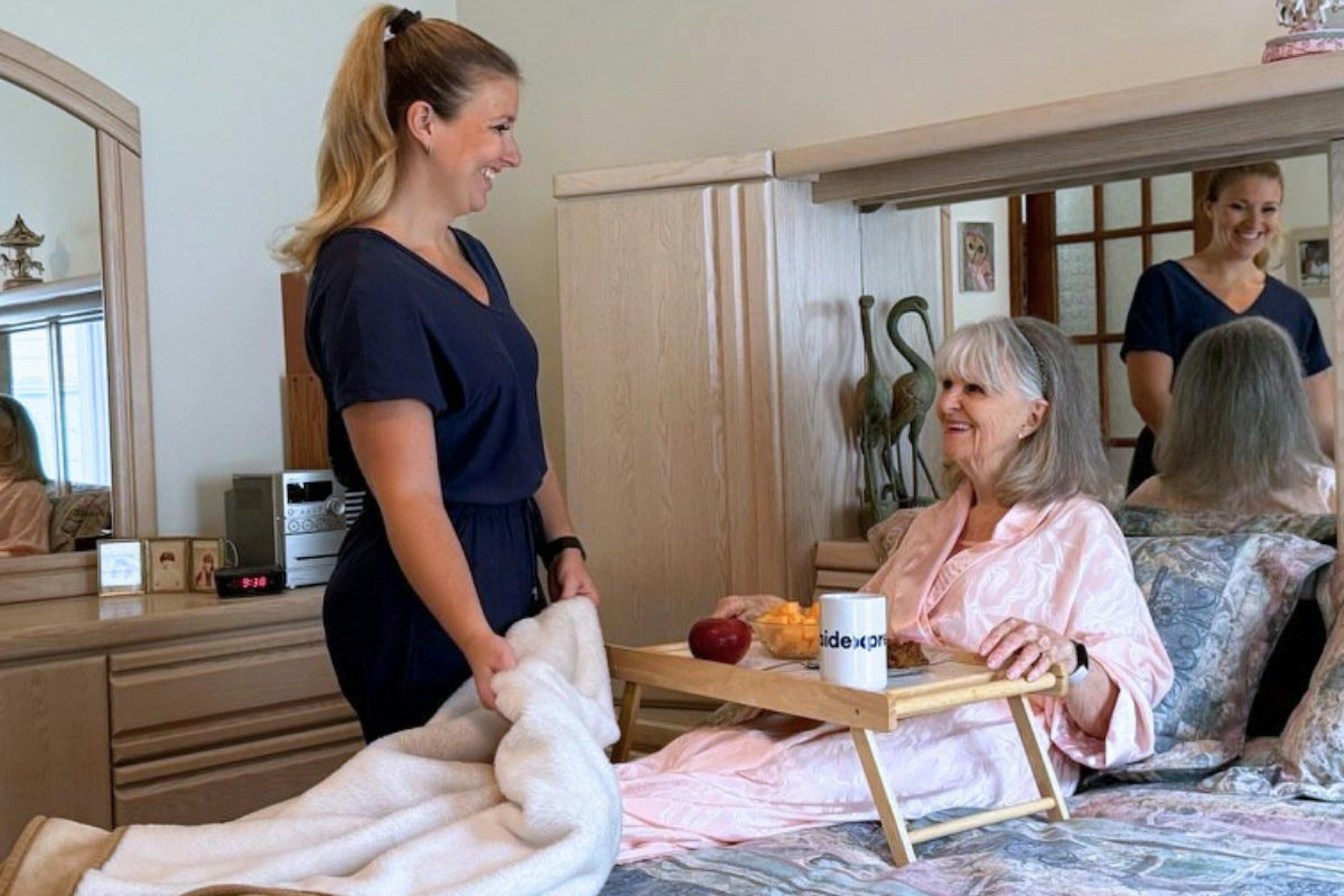 une jeune préposée aux bénéficaires donnant des soins à une femme qui est en convalescence dans sa maison