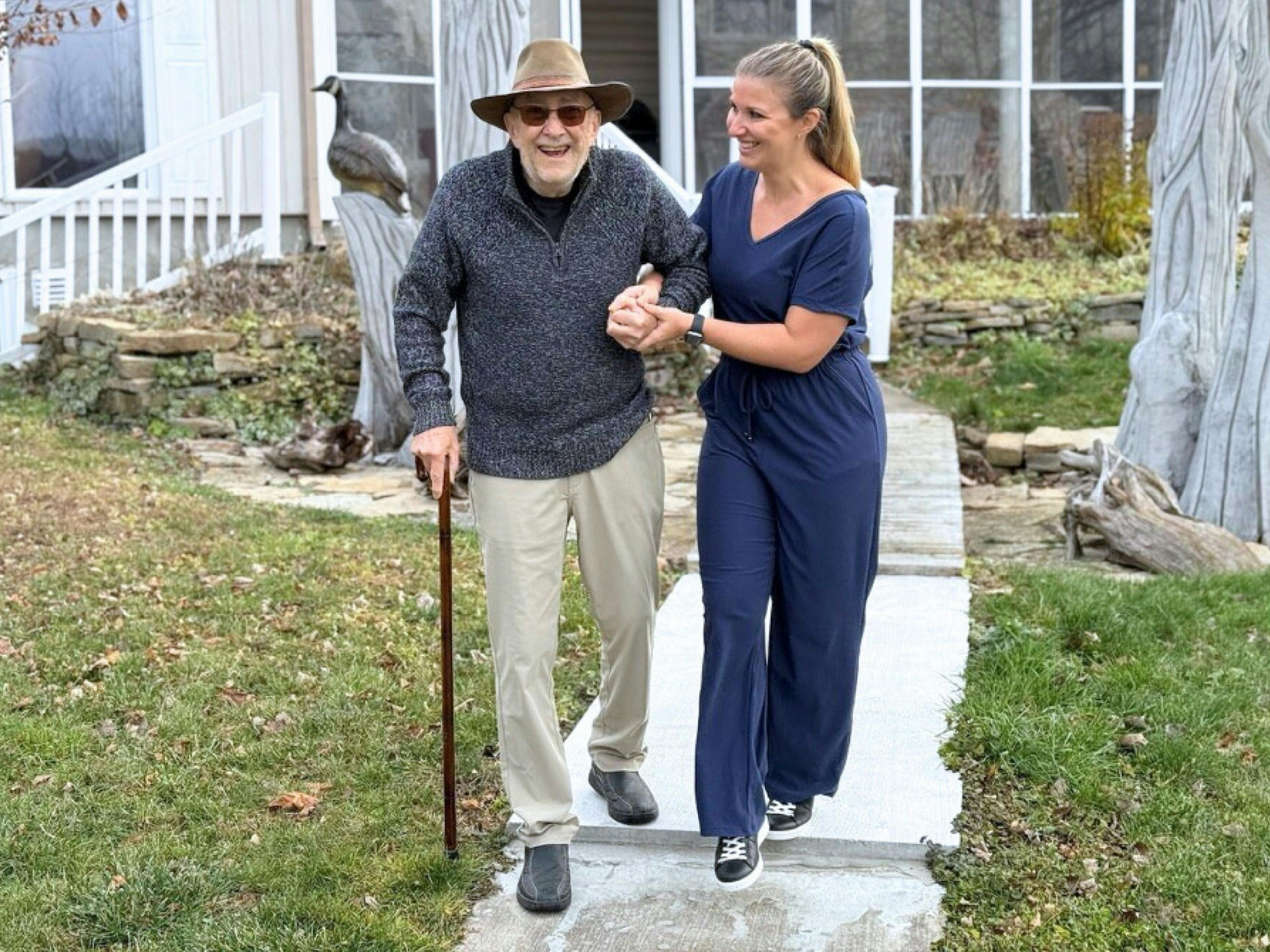 une aidante accompagne une personne âgée pour une sortie à l'extérieur de son domicile