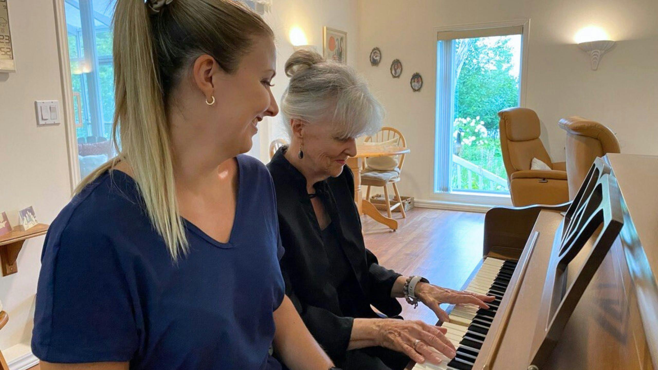une aidante qui partage un moment agréable au piano avec une personne âgée.