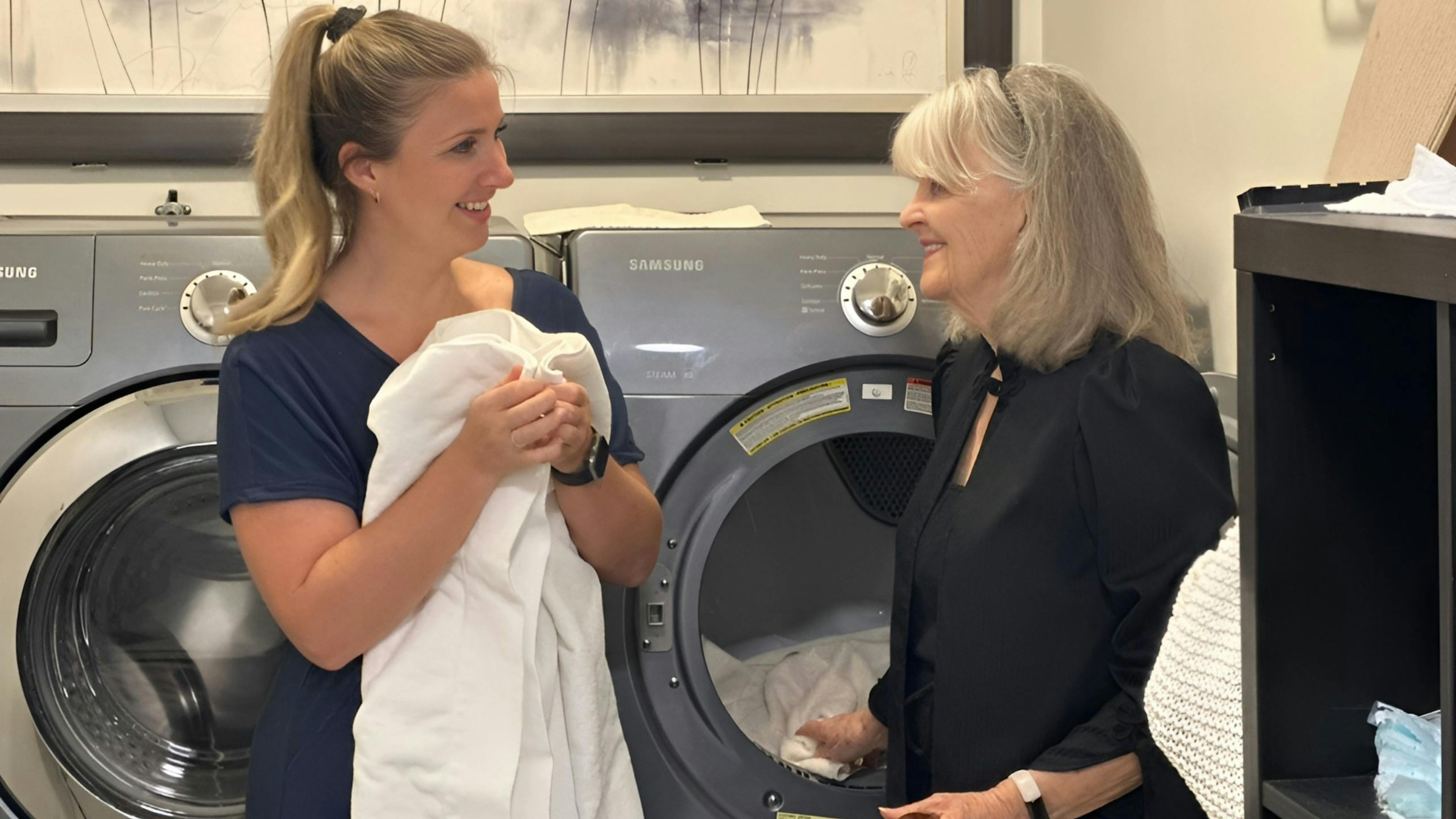 Une femme de ménage fait la lessive au domicile d'une personne âgée