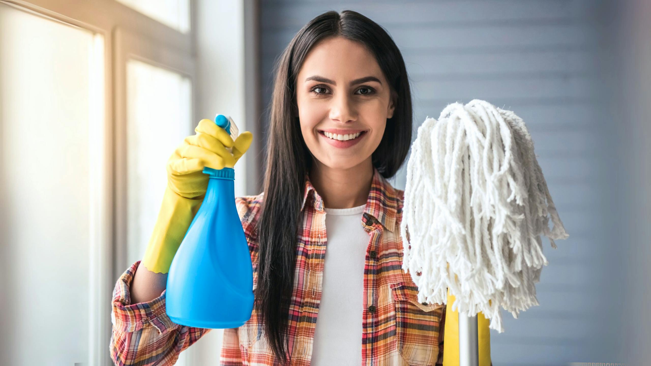 Une femme de ménage effectuant un grand ménage en profondeur à domicile, nettoyant murs et électroménagers pour un intérieur impeccable.