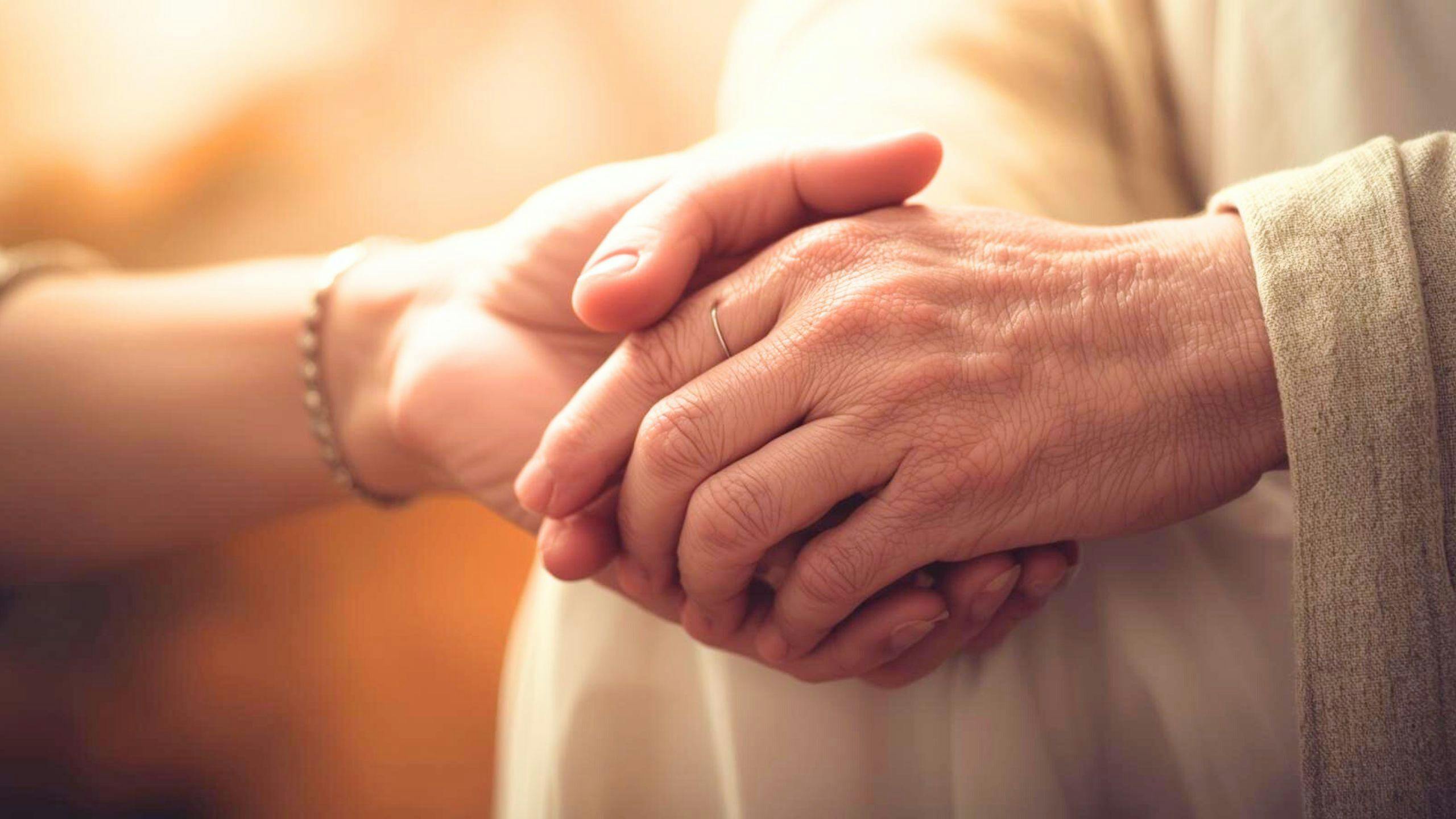 Personne en fin de vie accompagnée par un aidant dans un environnement calme et respectueux à domicile.