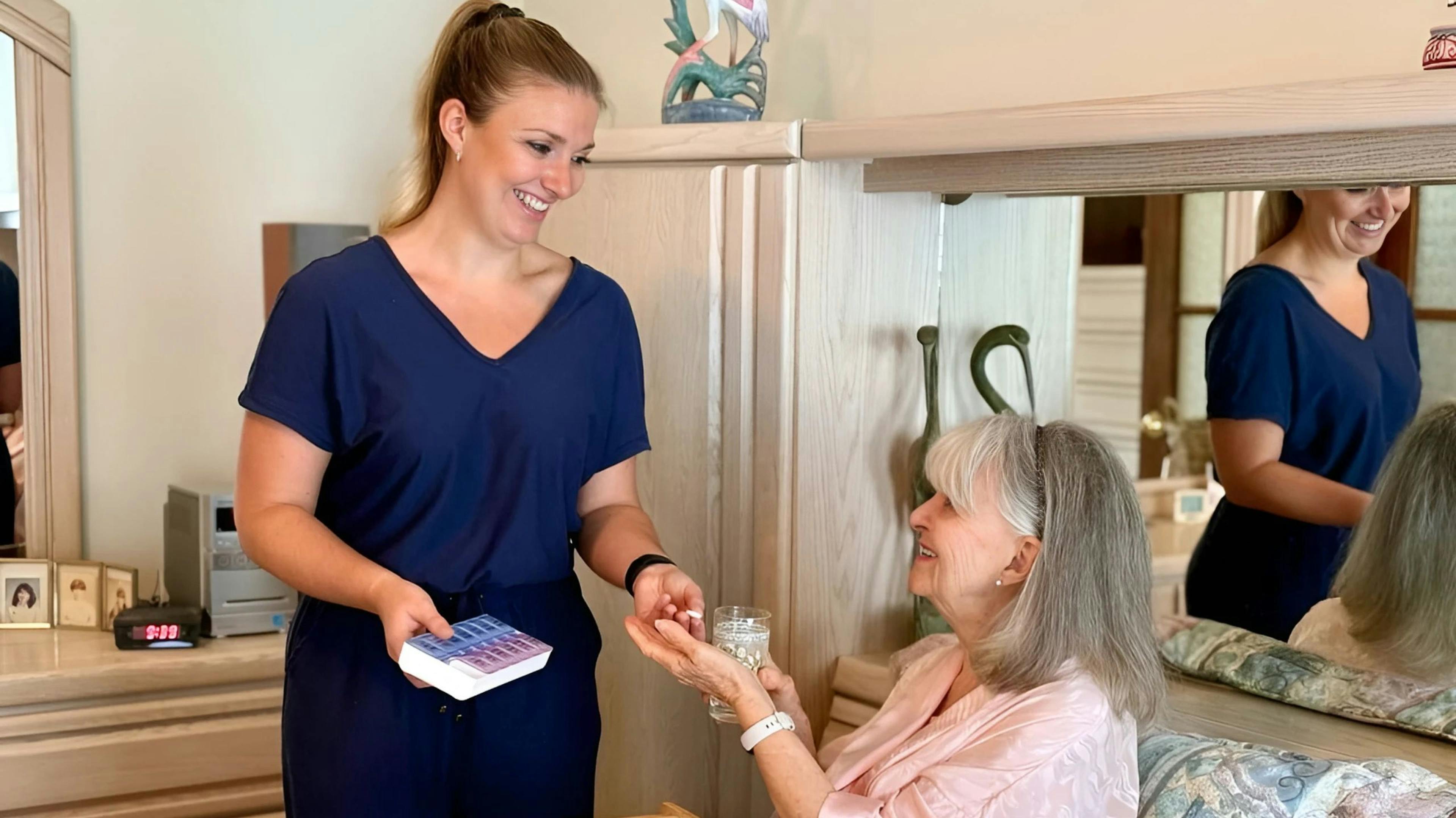 une préposée aux bénéficiaires qui donne les médicaments à une femme âgée en convalescence dans sa maison