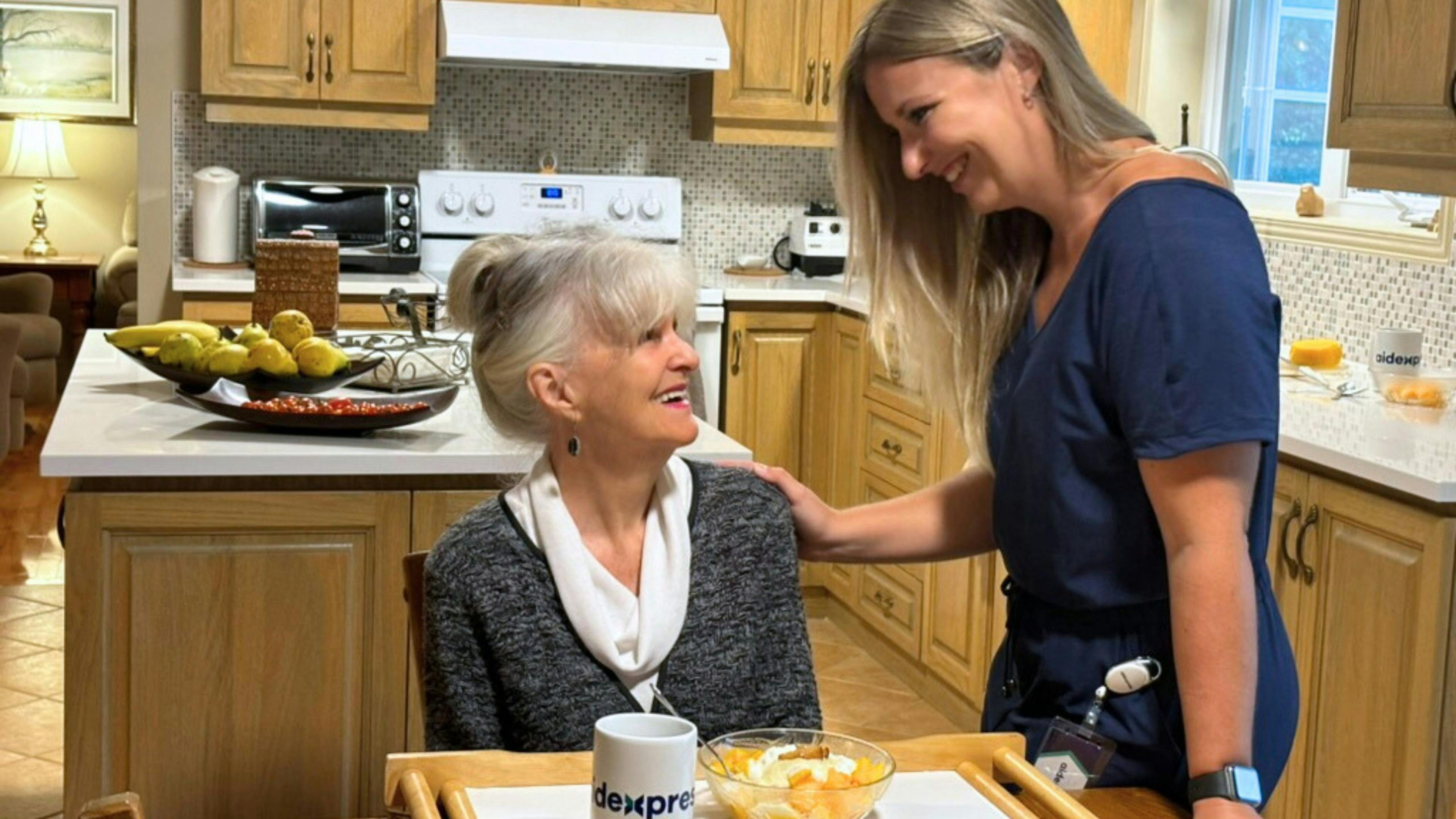 une femme âgée sourianterecevant de l'aide personnalisé à domicile d'Aidexpress.