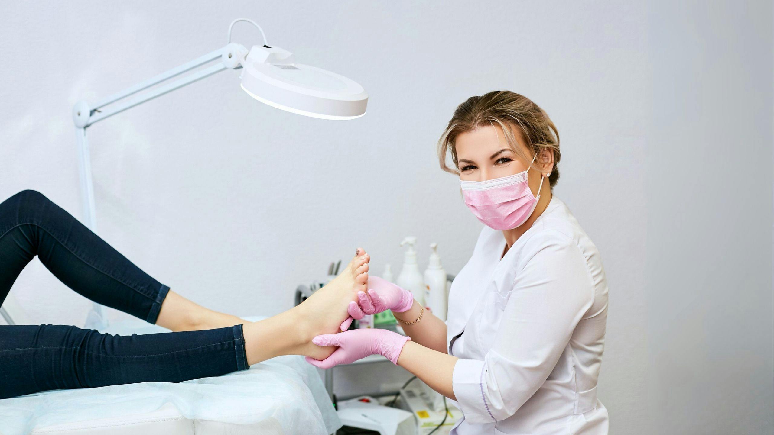 Infirmière auxiliaire en soins podologiques effectuant un soin des pieds à une personne âgée, illustrant un emploi humain et professionnel au sein d’Aidexpress.