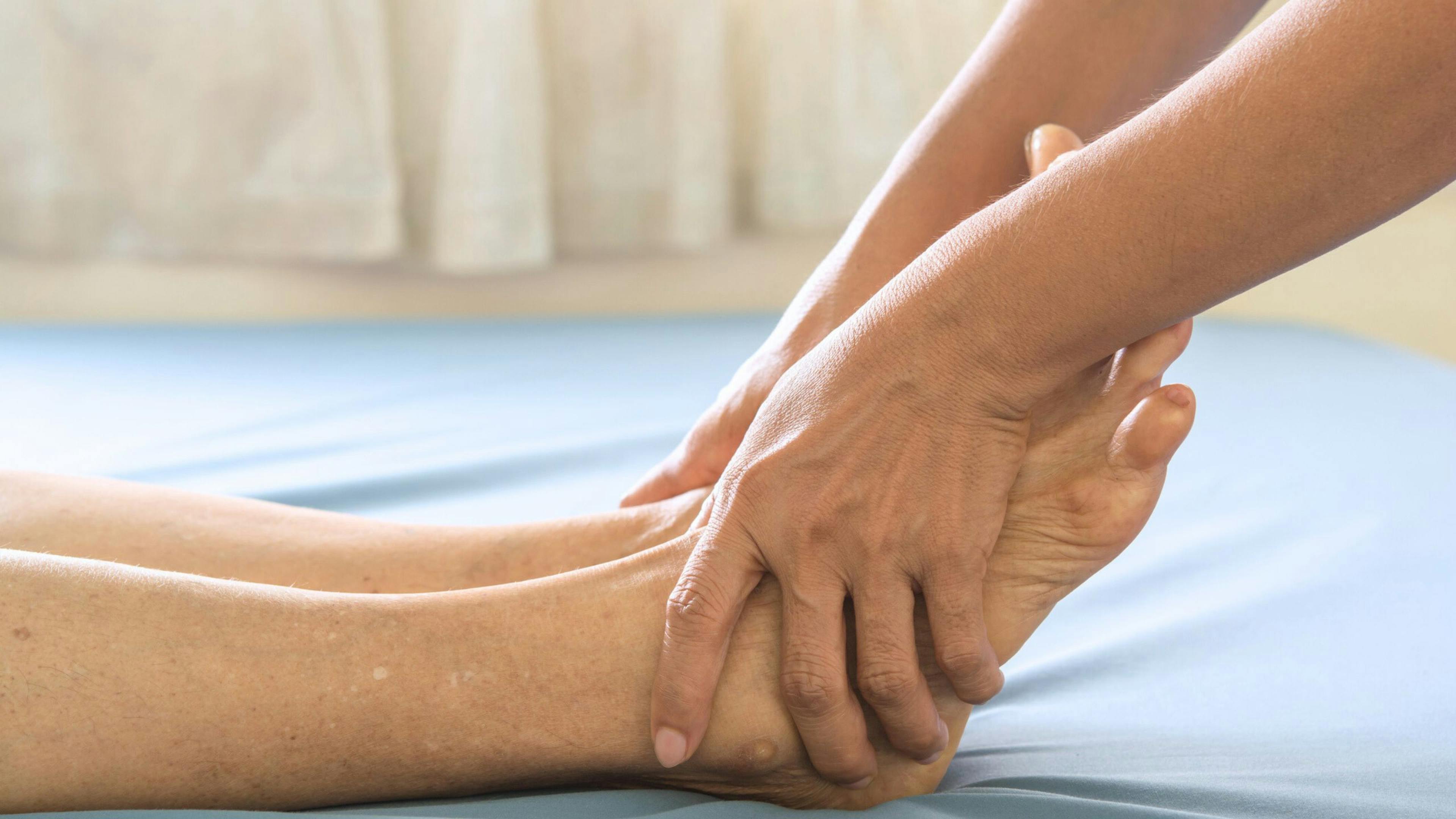 Podologue prodiguant un soin des pieds à une personne âgée, illustrant un emploi professionnel et bienveillant en santé préventive chez Aidexpress.