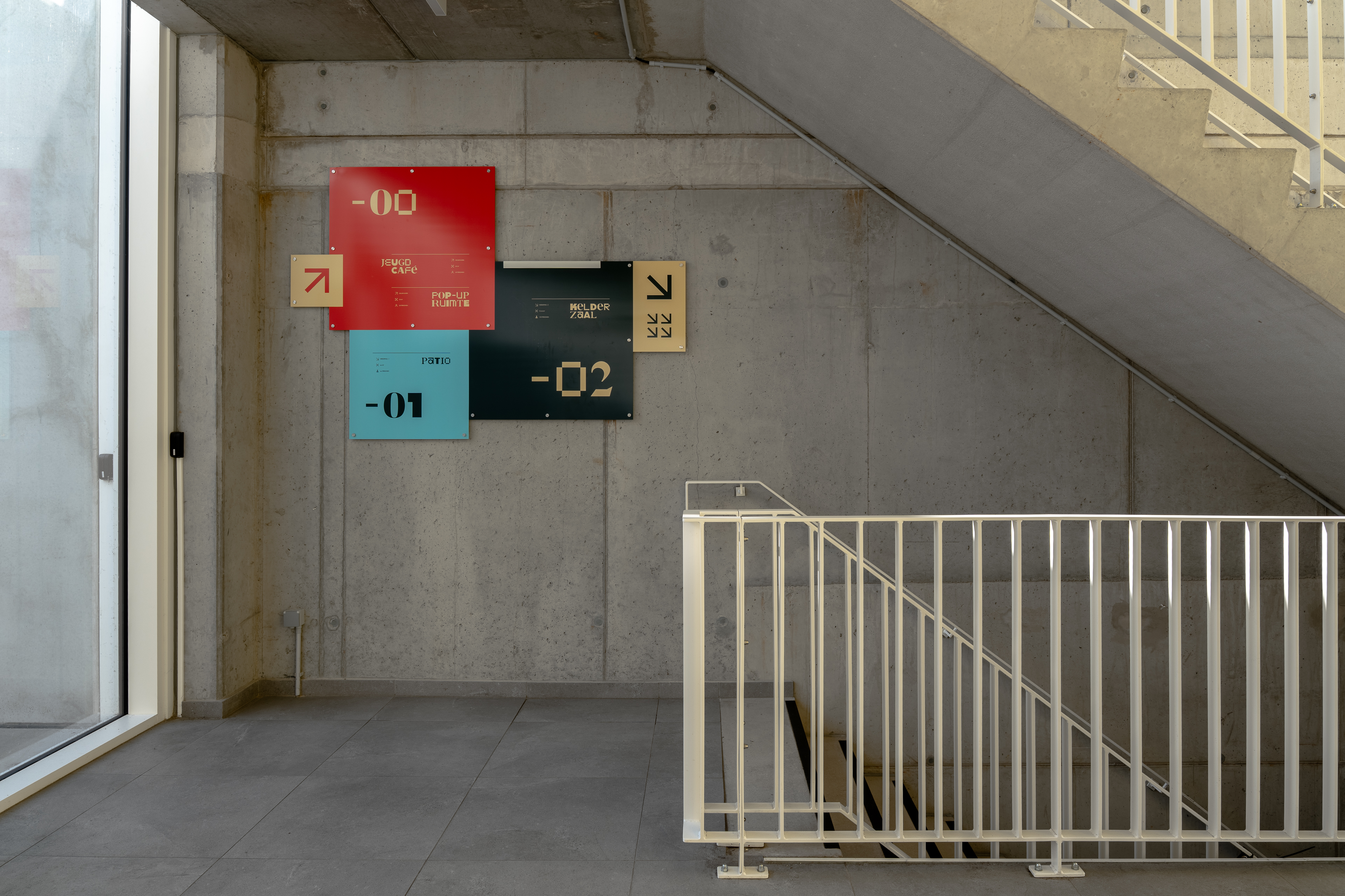 Betontrap en muur met gekleurde wegwijzers naar verschillende verdiepingen.