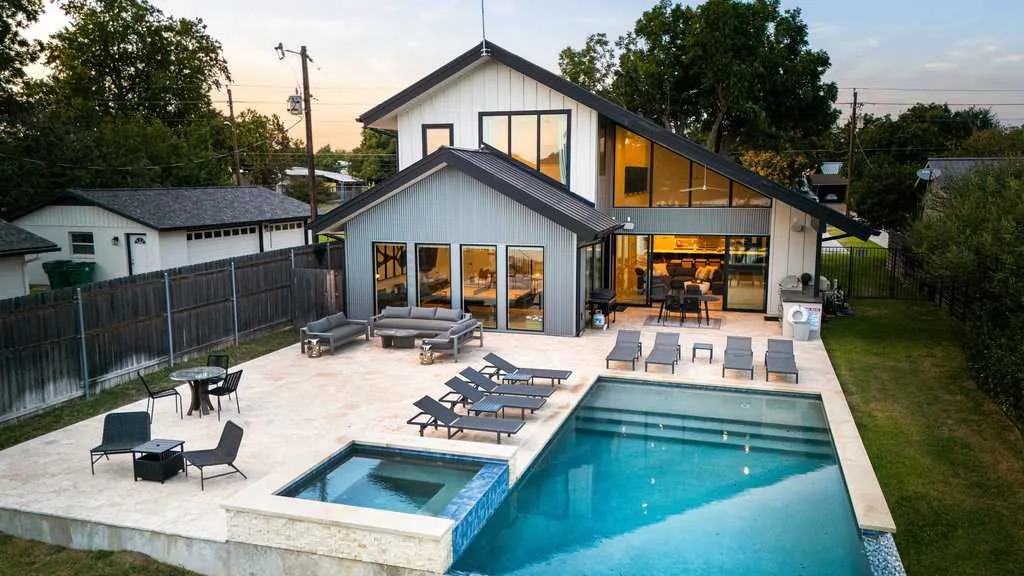 Modern Bach Bros Properties rental at dusk with a pool, hot tub, lounge chairs and an outdoor seating area