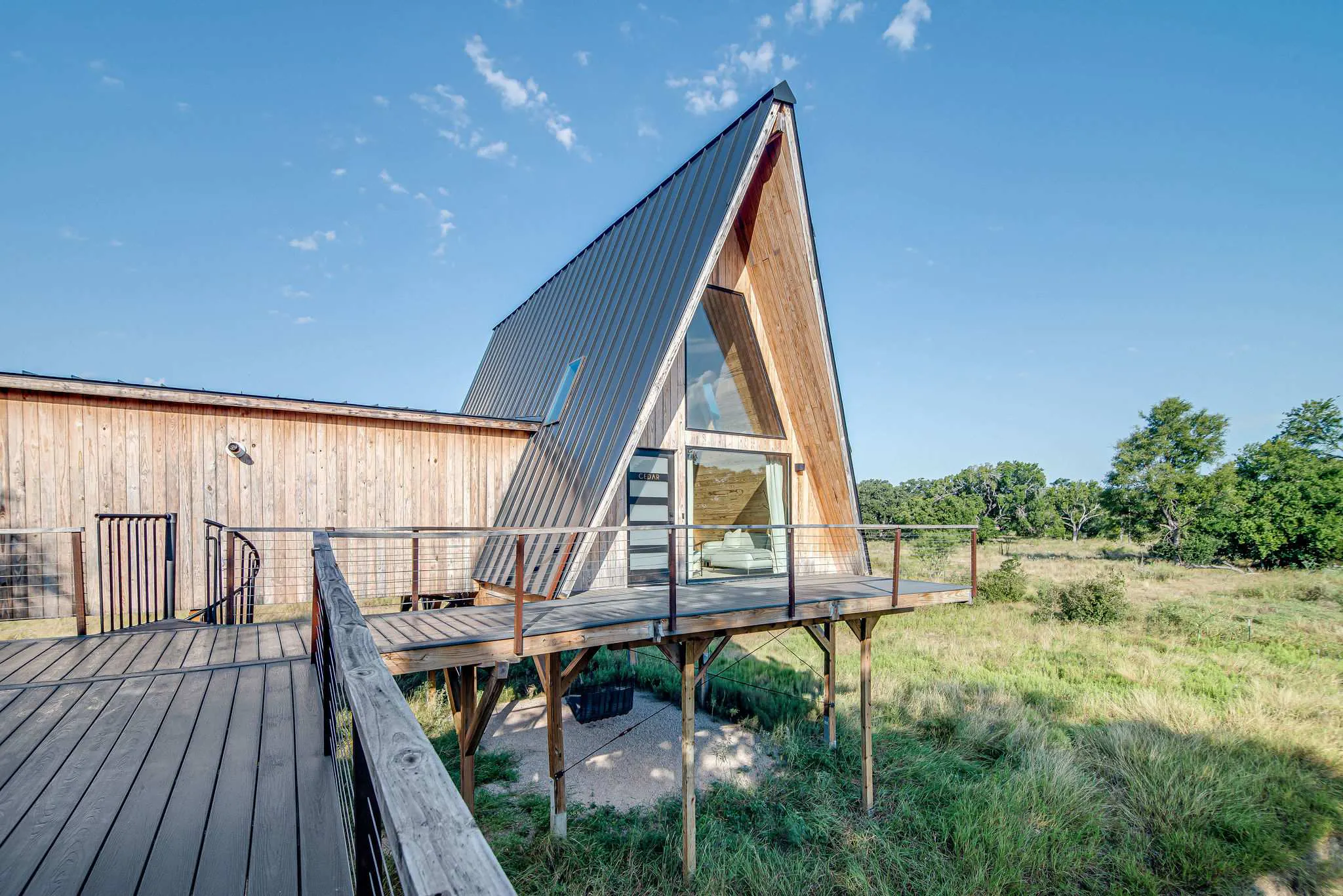 A-frame cabin managed by Bach Bros Properties with a metal roof and raised wooden deck in the Texas Hill Country