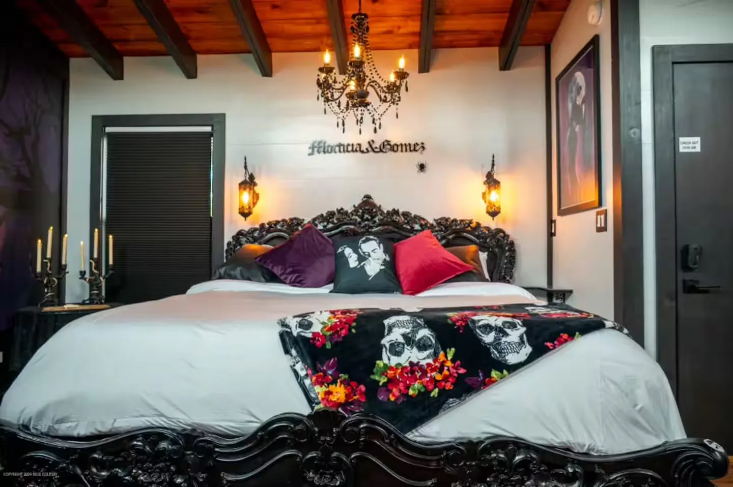Gothic bedroom in the Morticia and Gomez Addams treehouse in Sevierville, Tennessee, with a carved baroque king bed, skull throw and candle chandelier