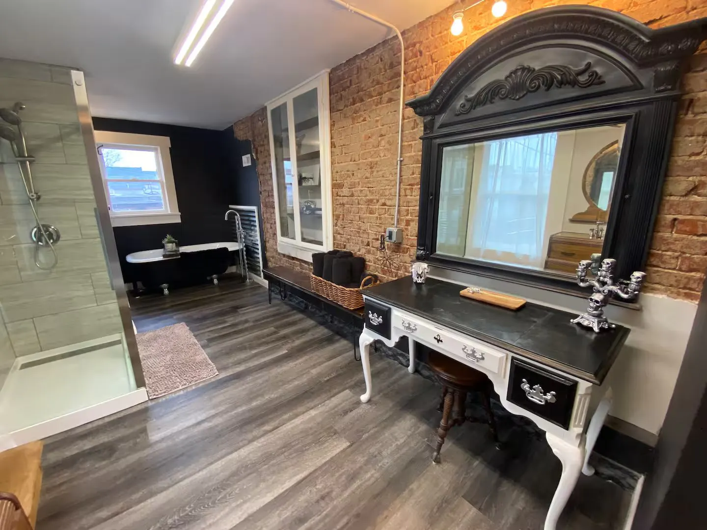 Bathroom at the Historic Morgue rental in Ozark, Missouri, with exposed brick, an antique vanity and a claw-foot tub
