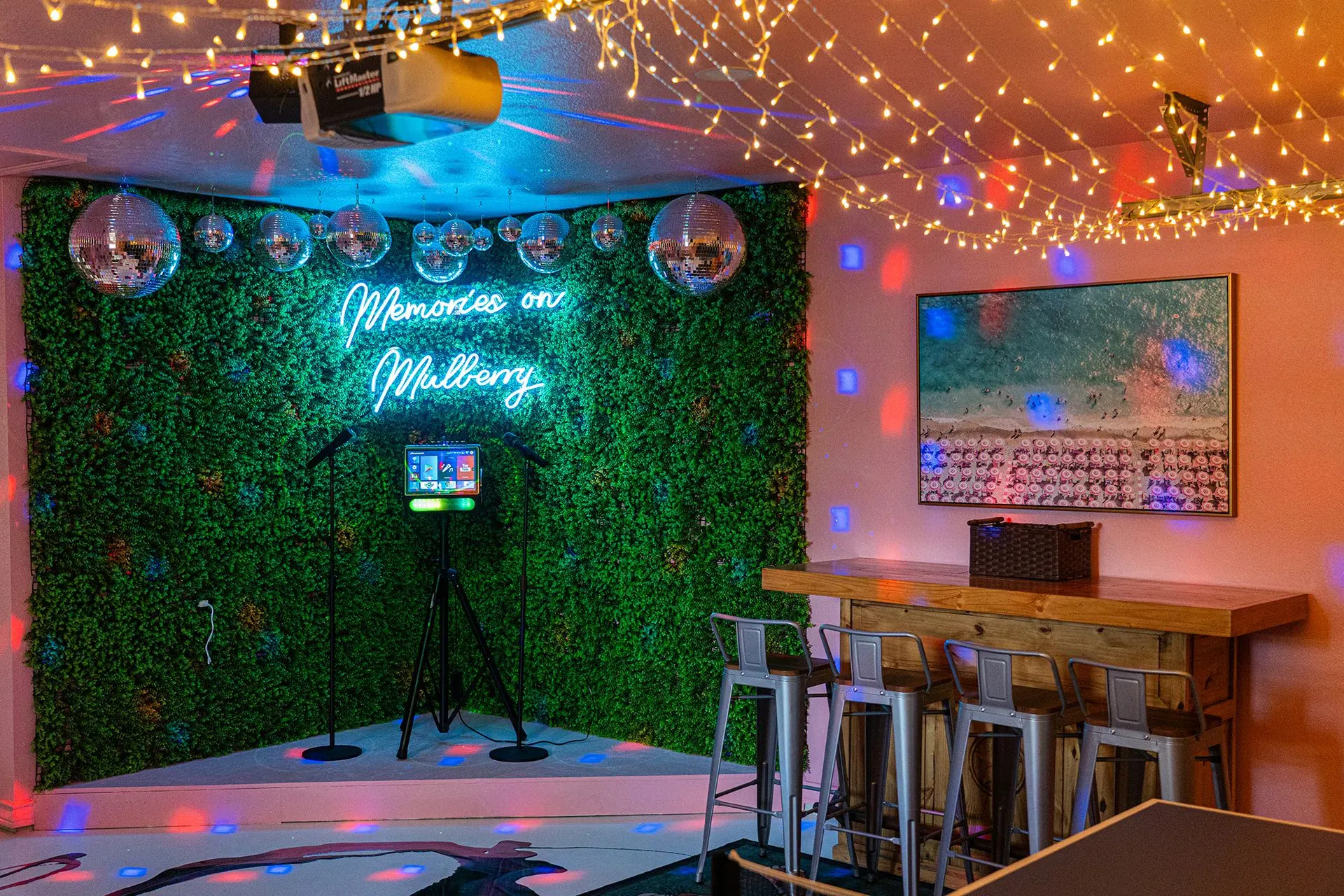 Karaoke room in a Bach Bros Properties rental with a neon sign, disco balls, a green wall and string lights