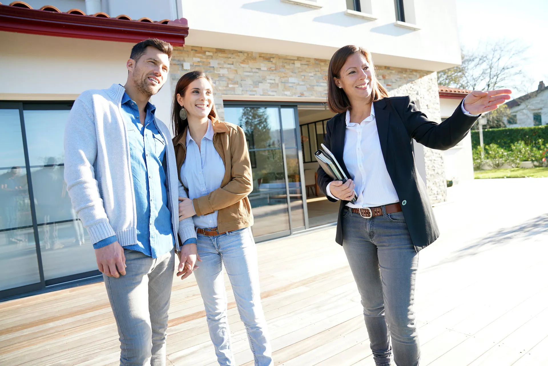 Couple with a real-estate agent visiting a house for sale.