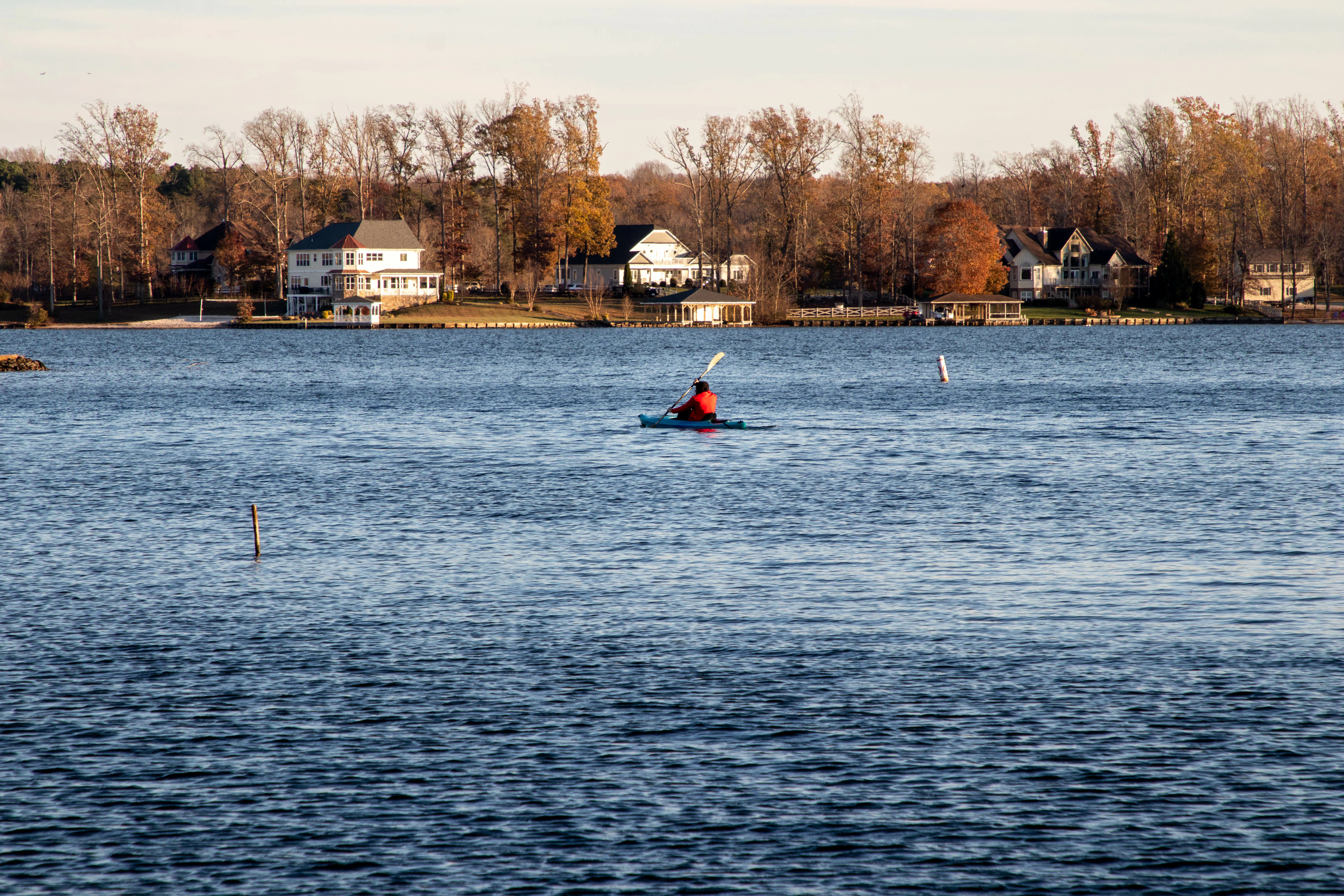 Kayaker on lake with homes seen on the shore