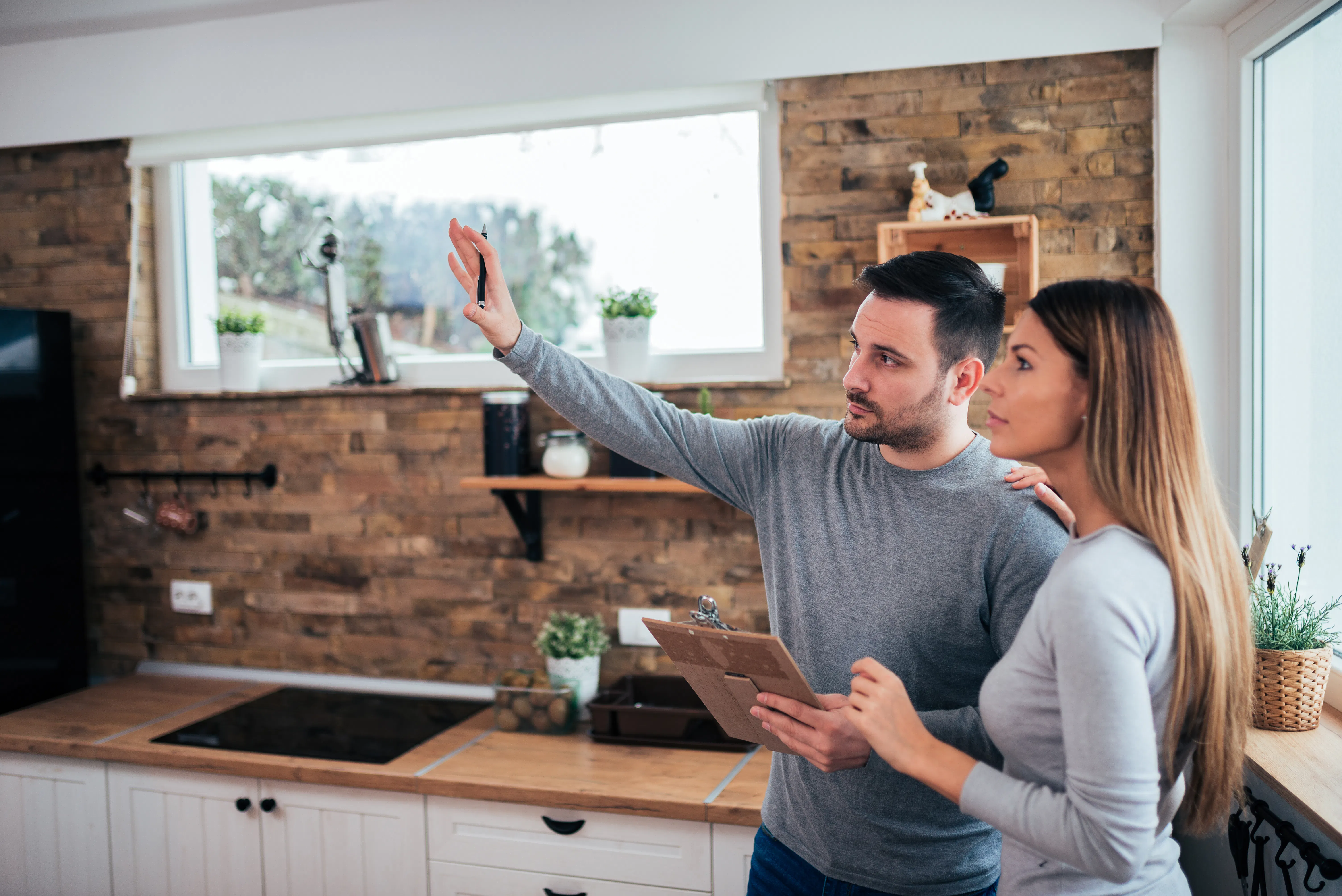 Man with clip board chatting with woman in kitchen