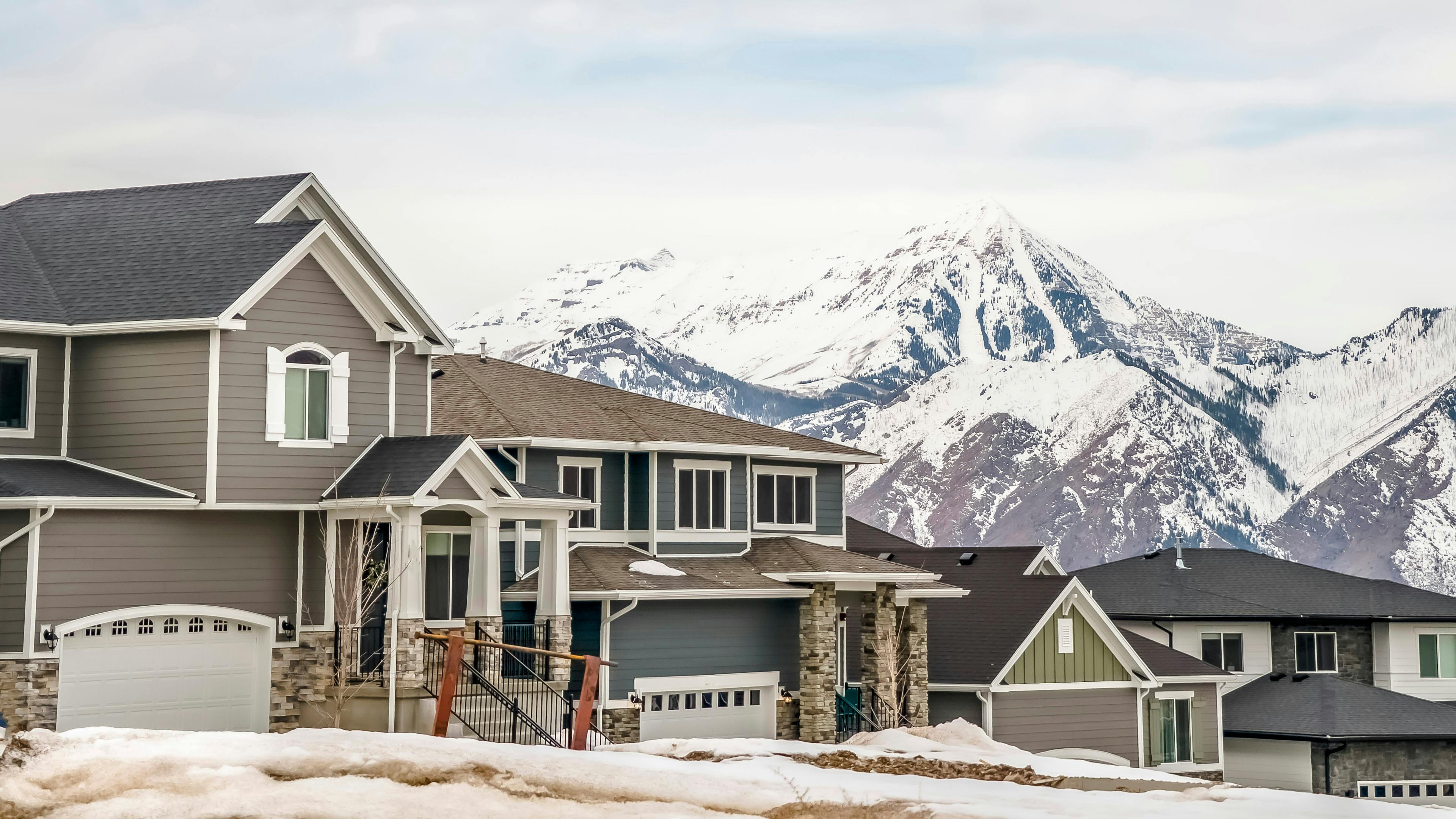 Panorama neighborhood with homes viewed against snowy mountain and cloudy sky&nbsp;