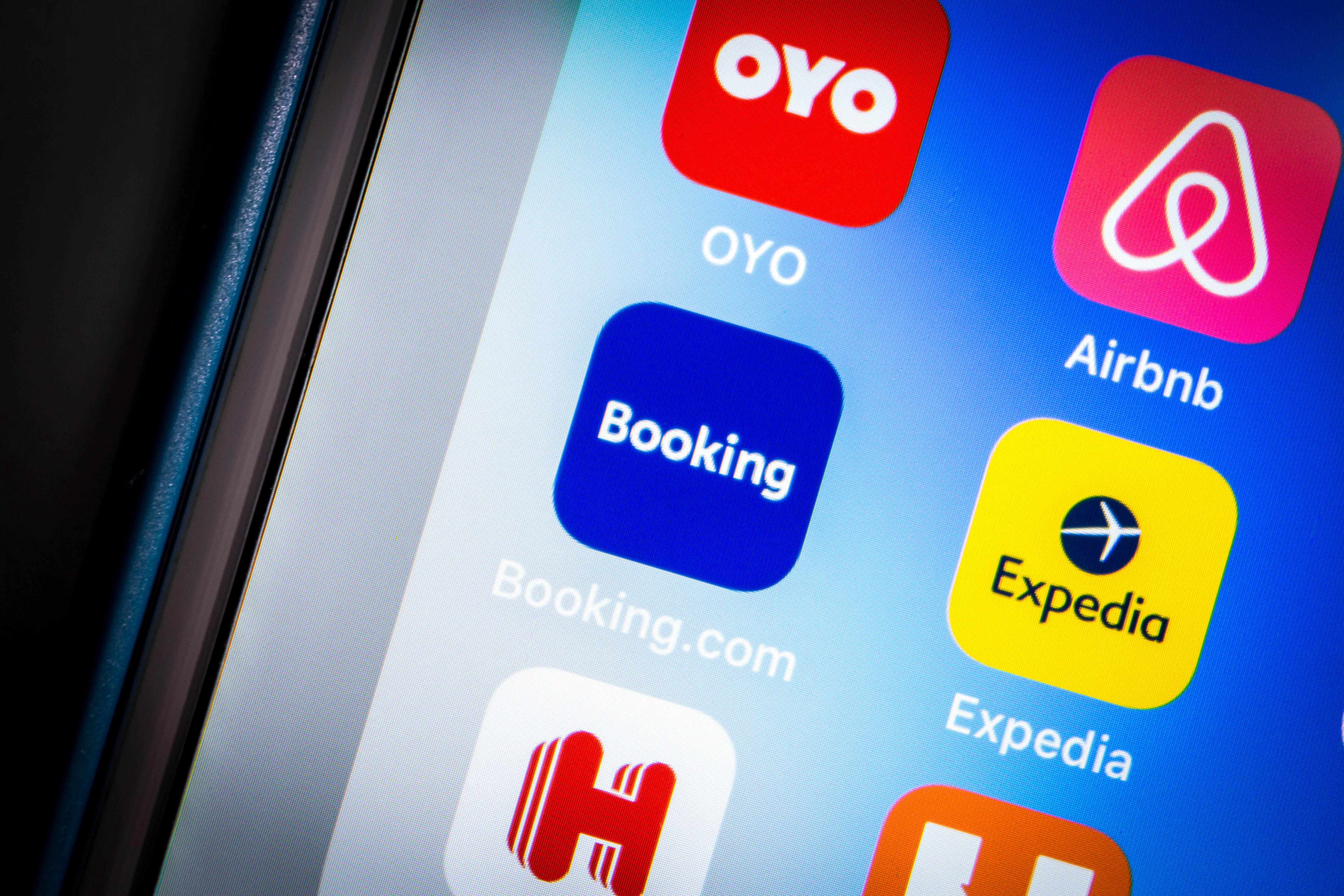 Booking.com app next to other travel apps on a cell phone.