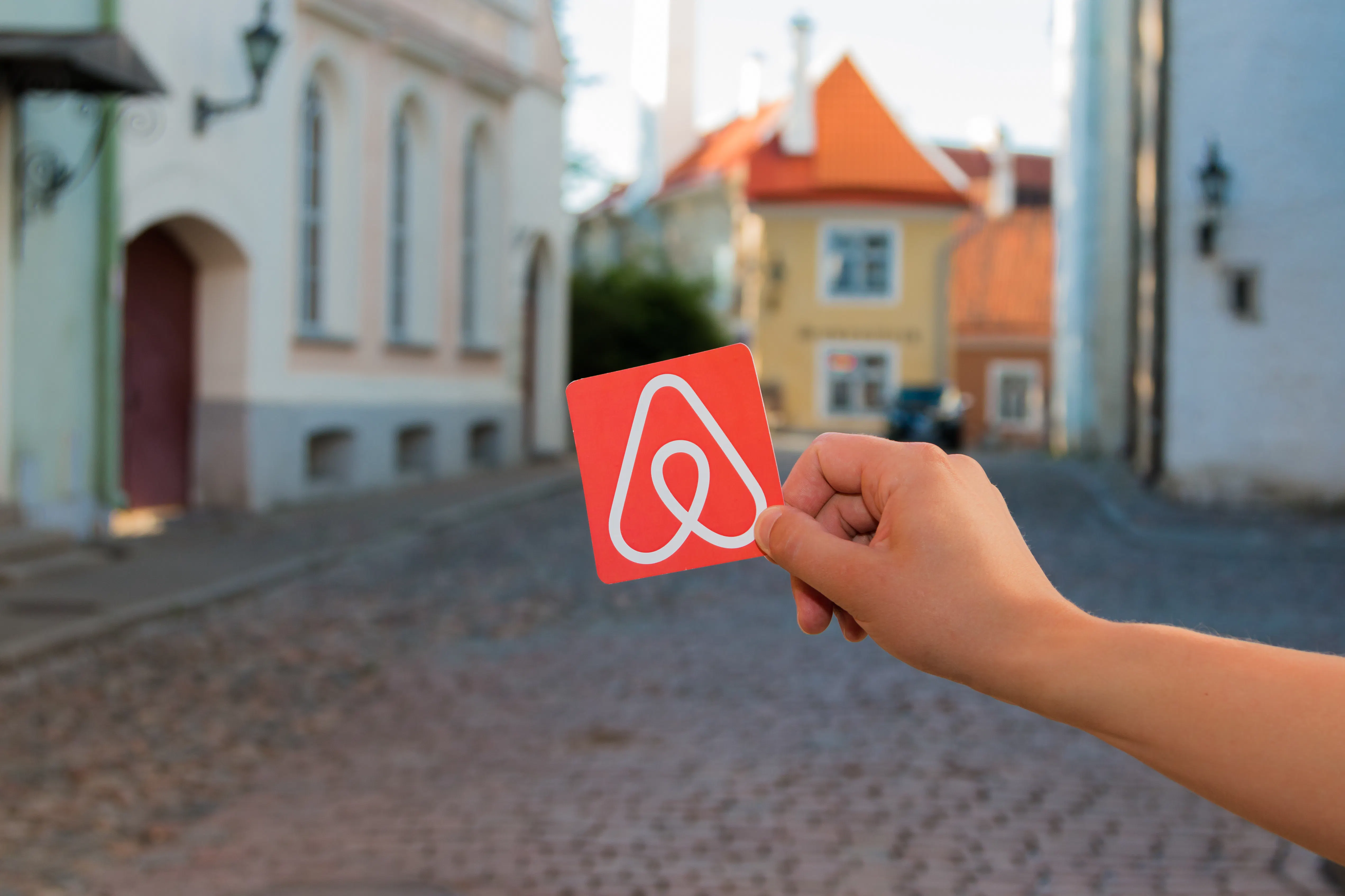 Card with the Airbnb logo in front of a town street.