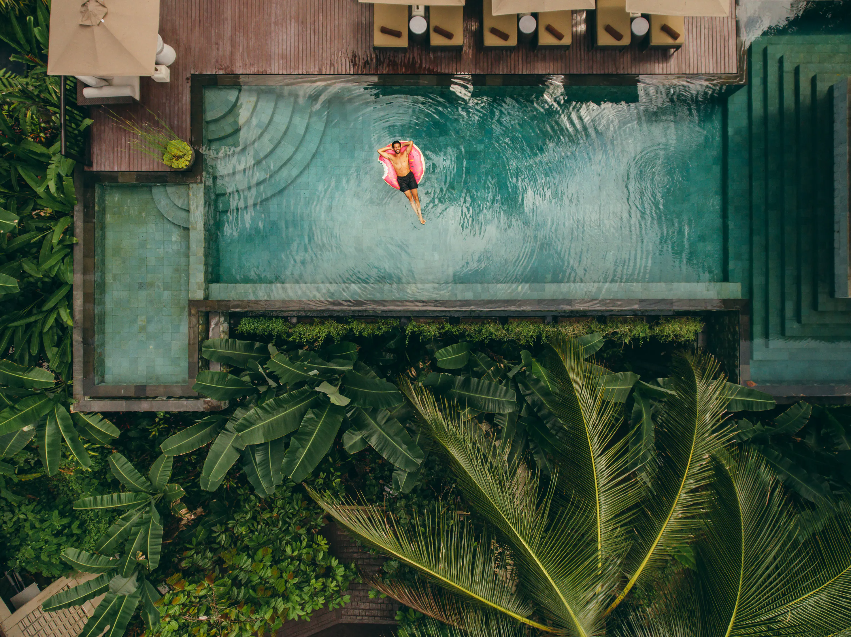 Young man relaxing in resort swimming pool.