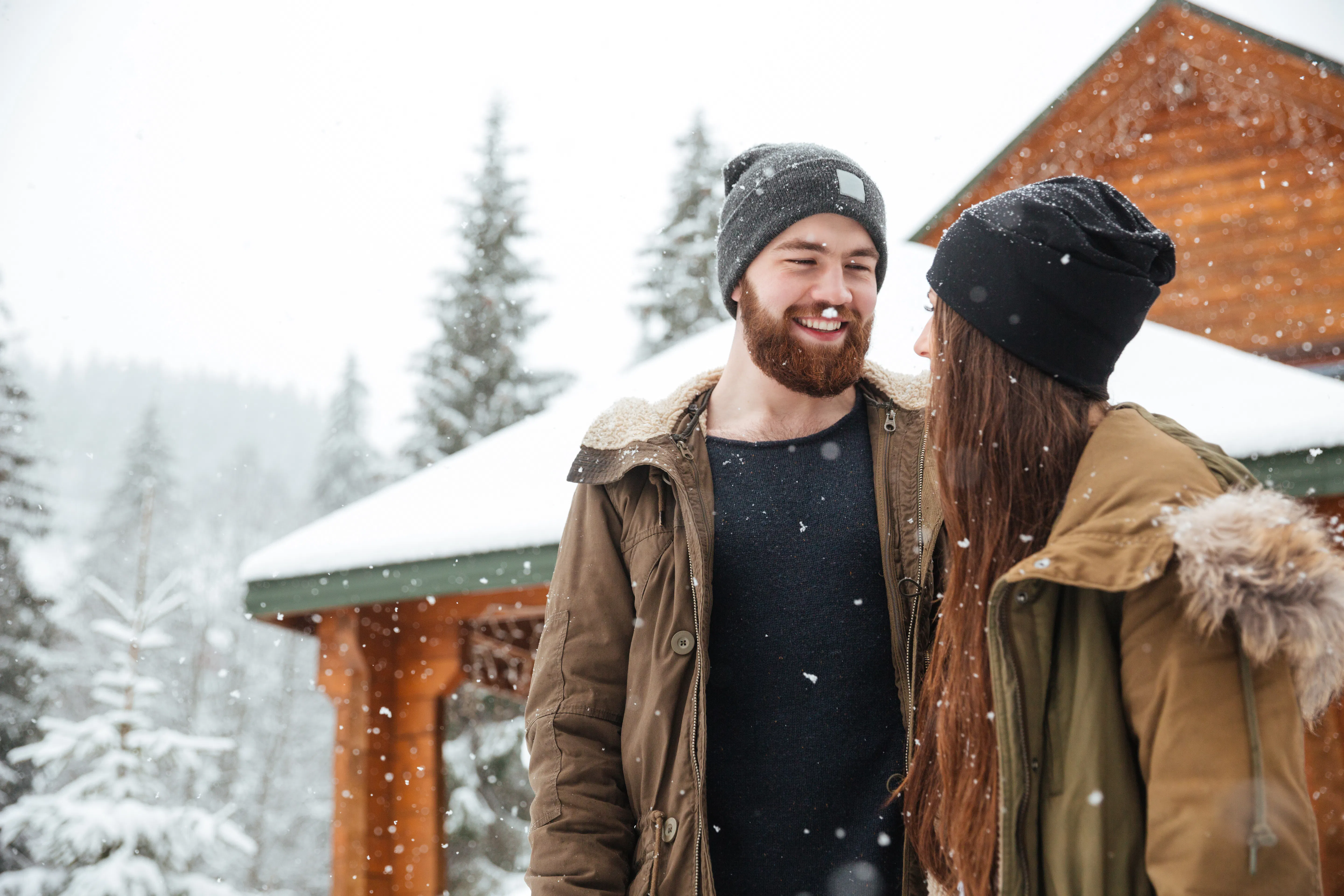 Couple standing near wooden cottage and laughing