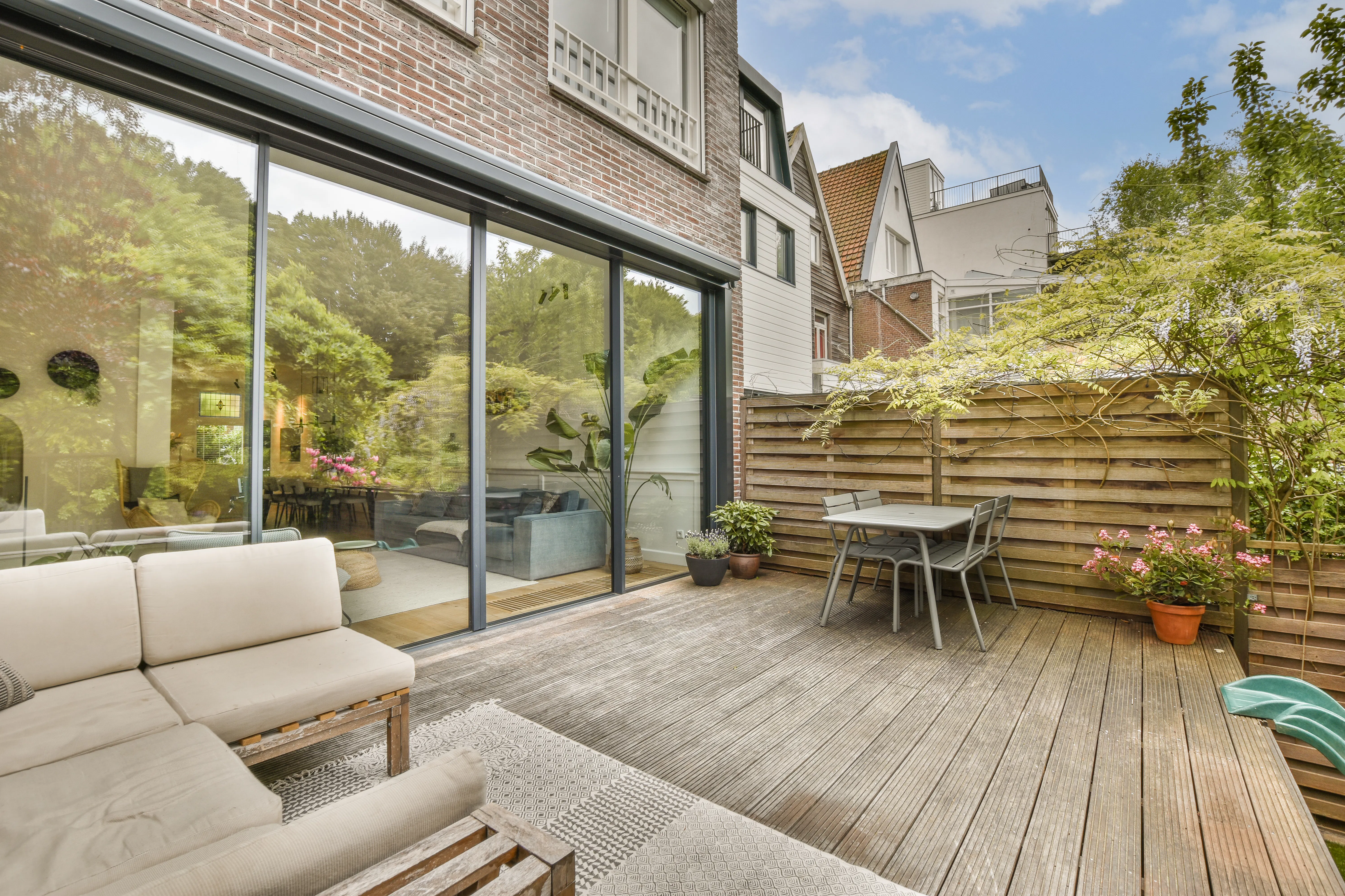 a patio with wooden decking and glass doors leading to an outdoor living area that looks out onto the street