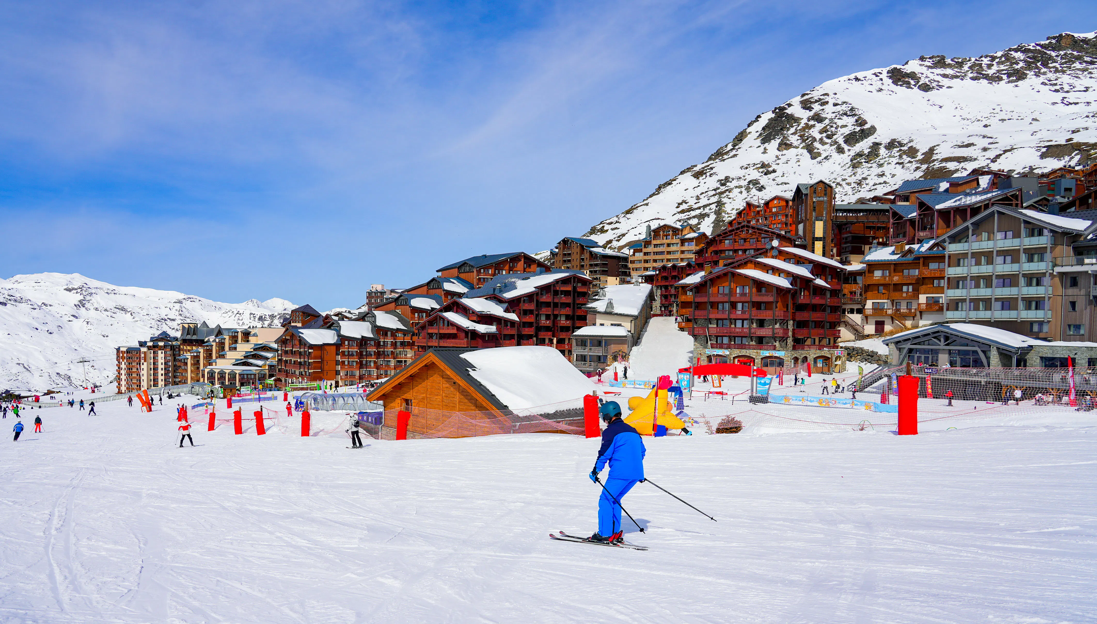 Snowy track going through a village of wooden chalets.