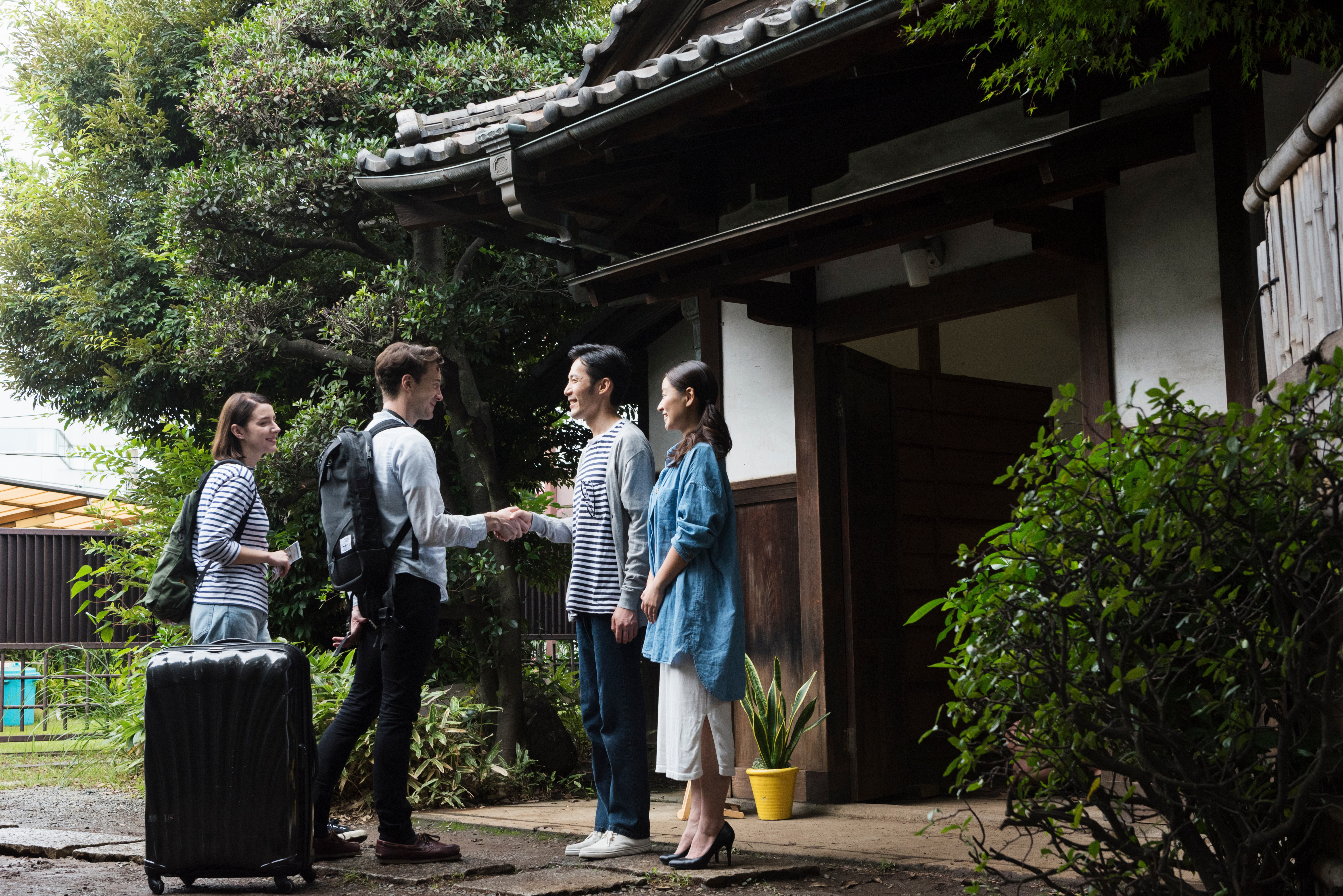 Couple greeting travelers outside home