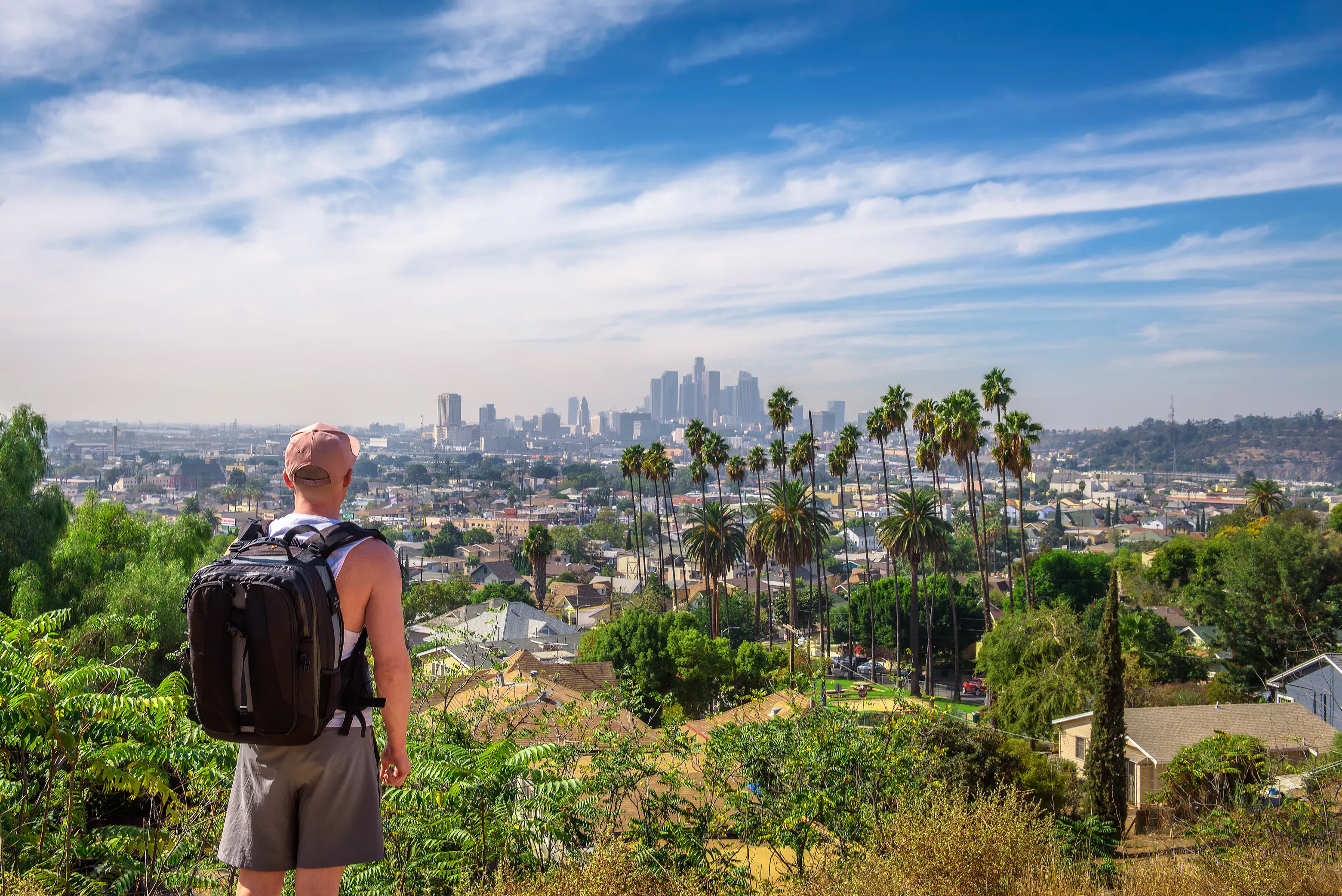 Man with backpack facing LA skyline
