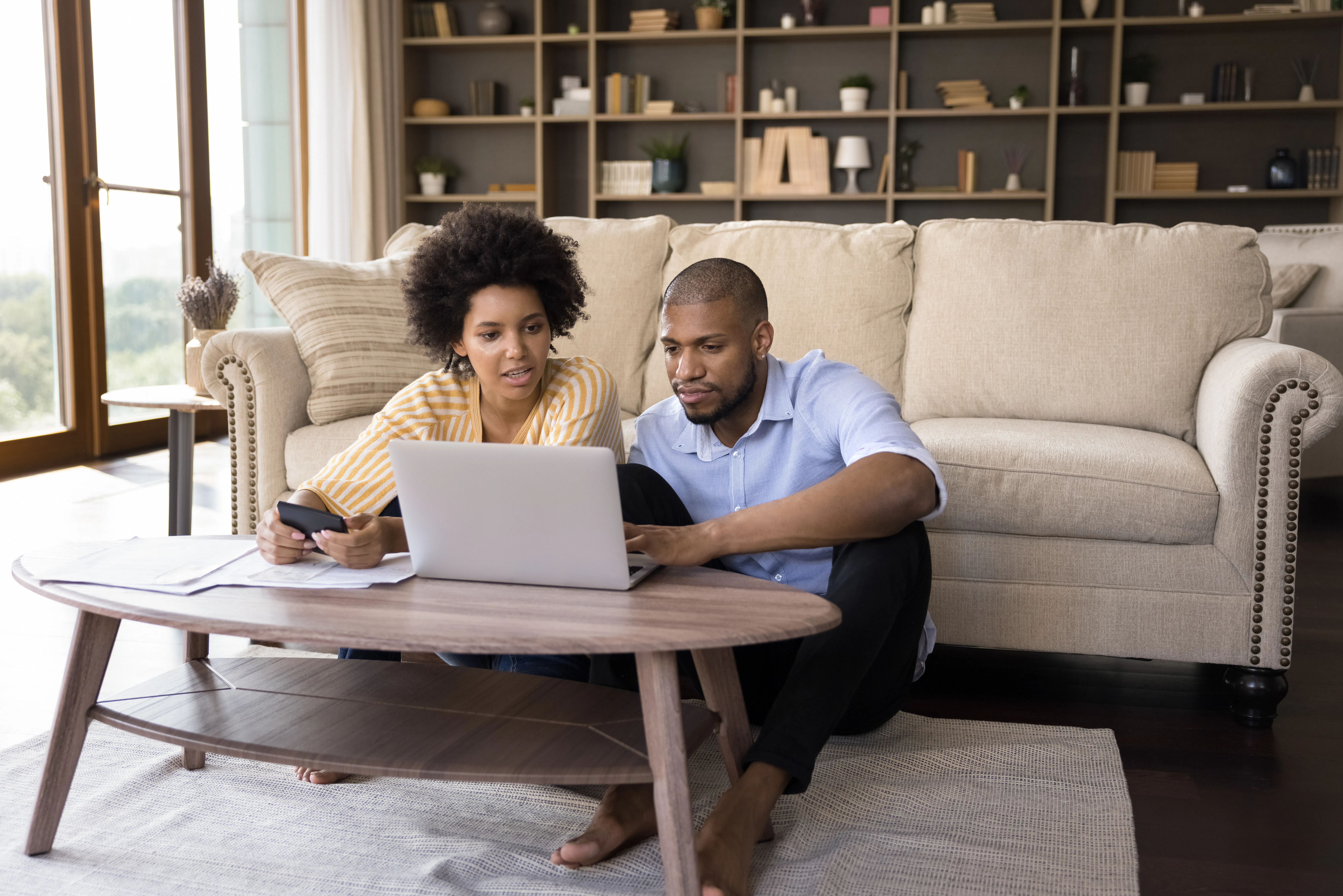 Two hosts reviewing documents and a laptop while assembling evidence for an Airbnb review removal request