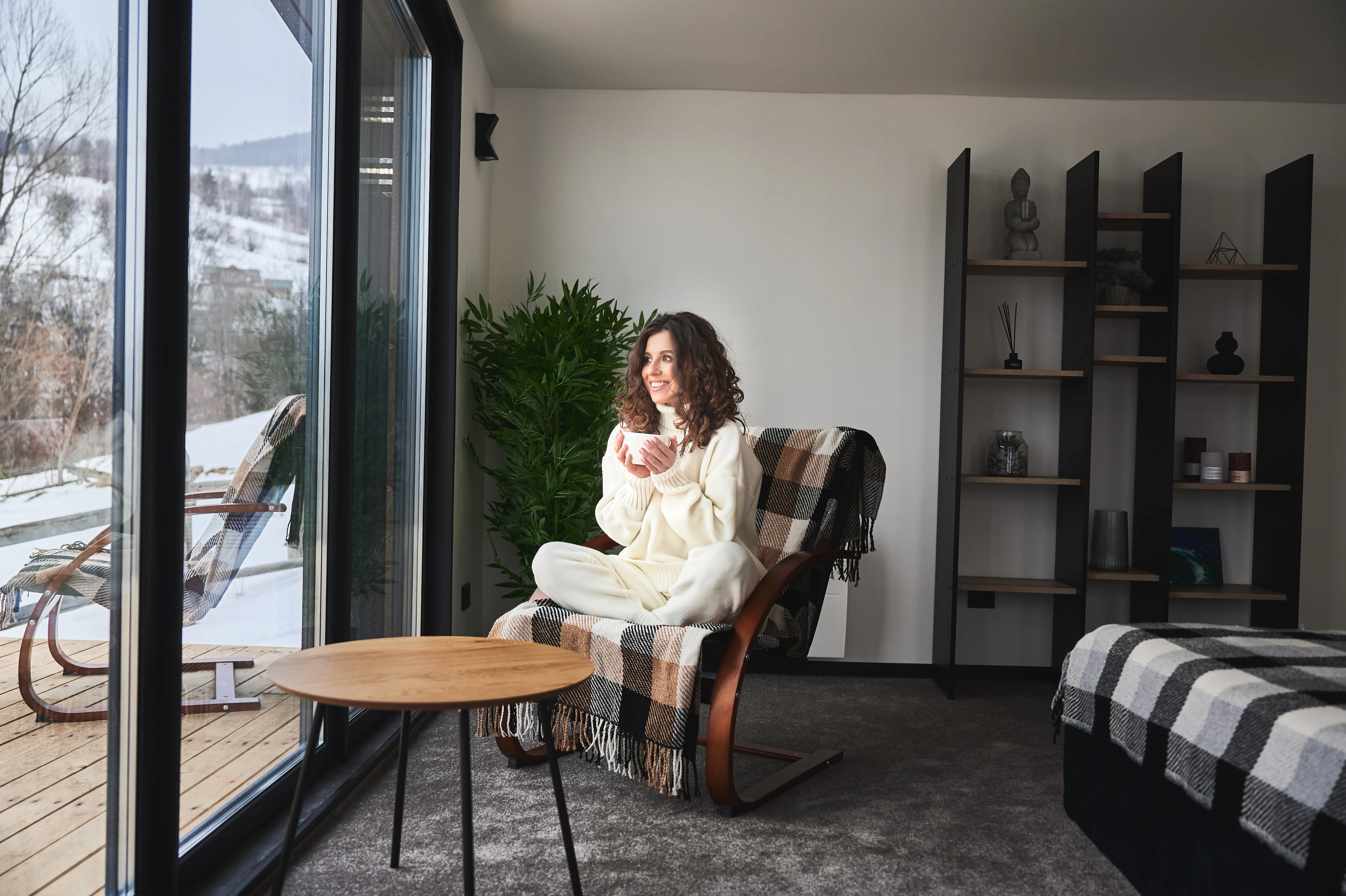 Curly haired young woman resting inside contemporary barn house in the mountains