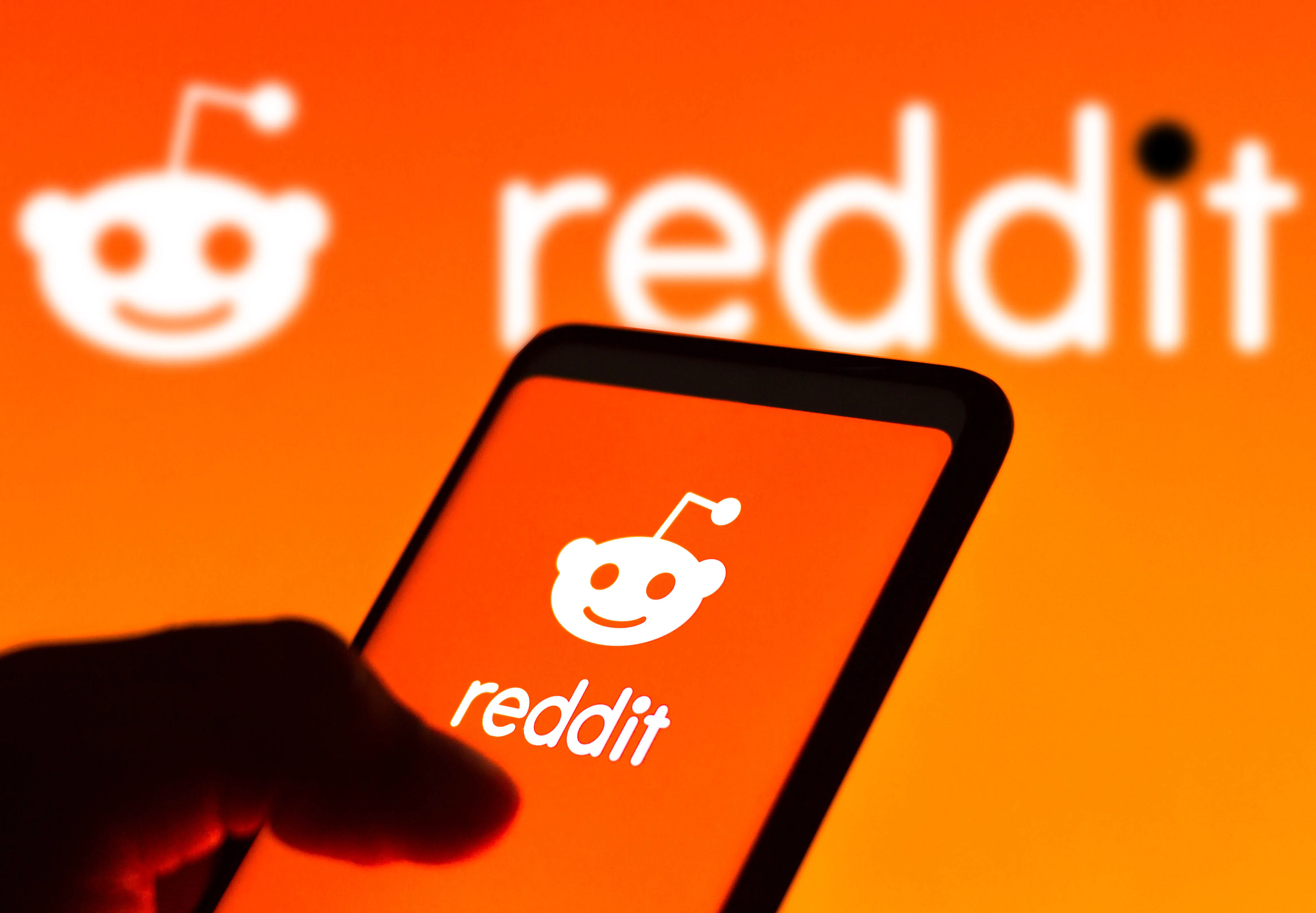 Reddit logo seen displayed on a smartphone and on the background