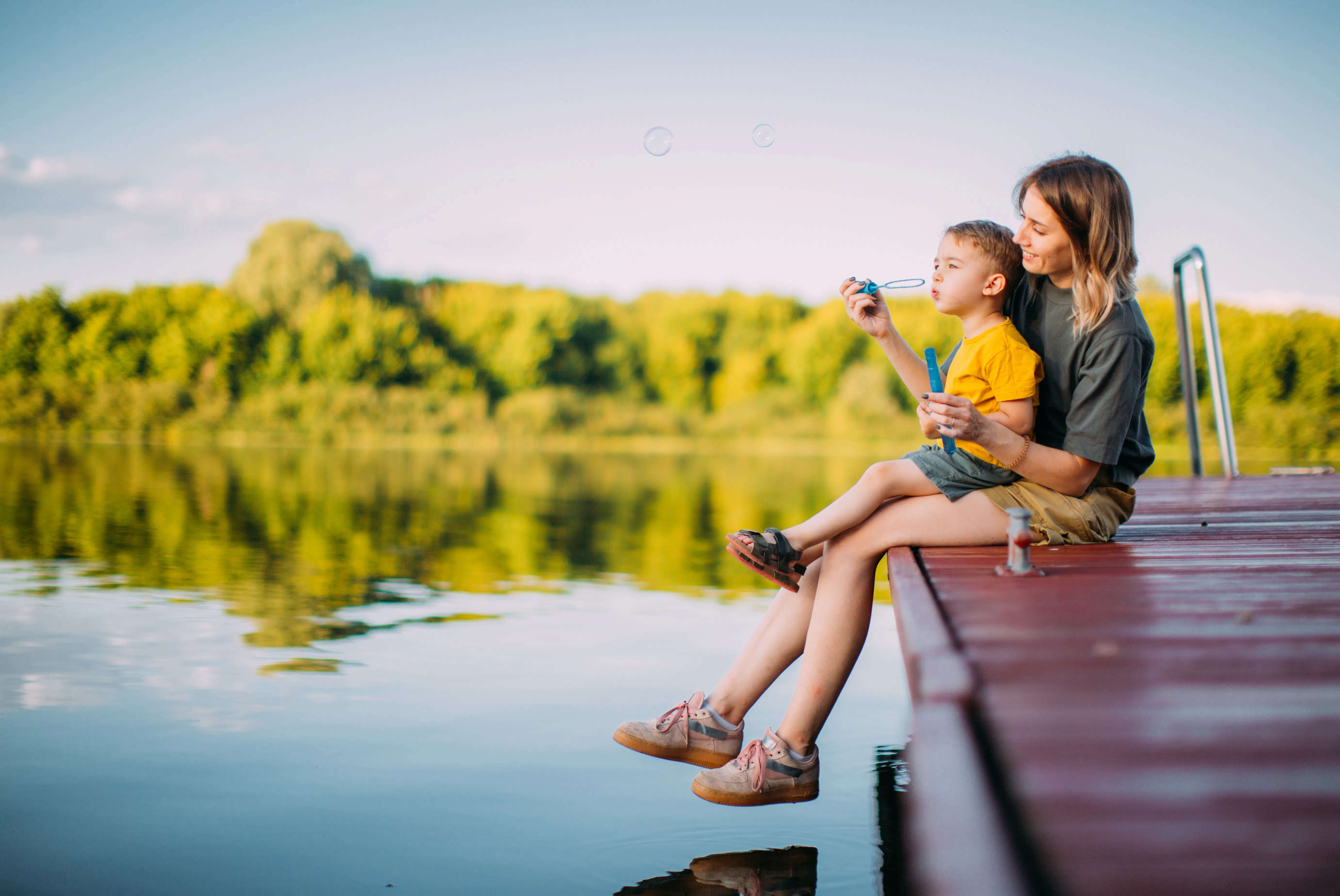 Mother and son blowing bubbles on dock
