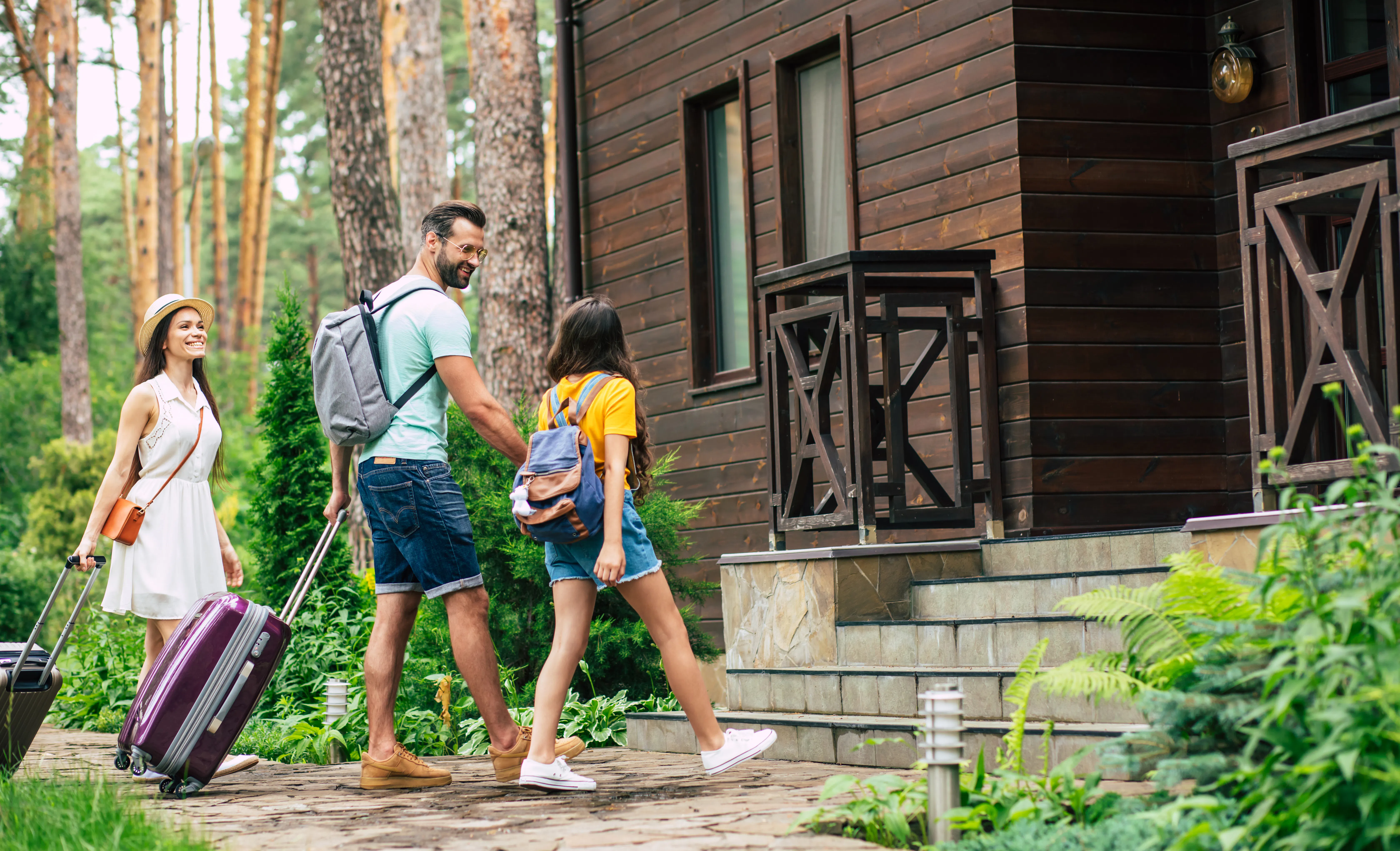 Family with suitcases approaching vacation rental