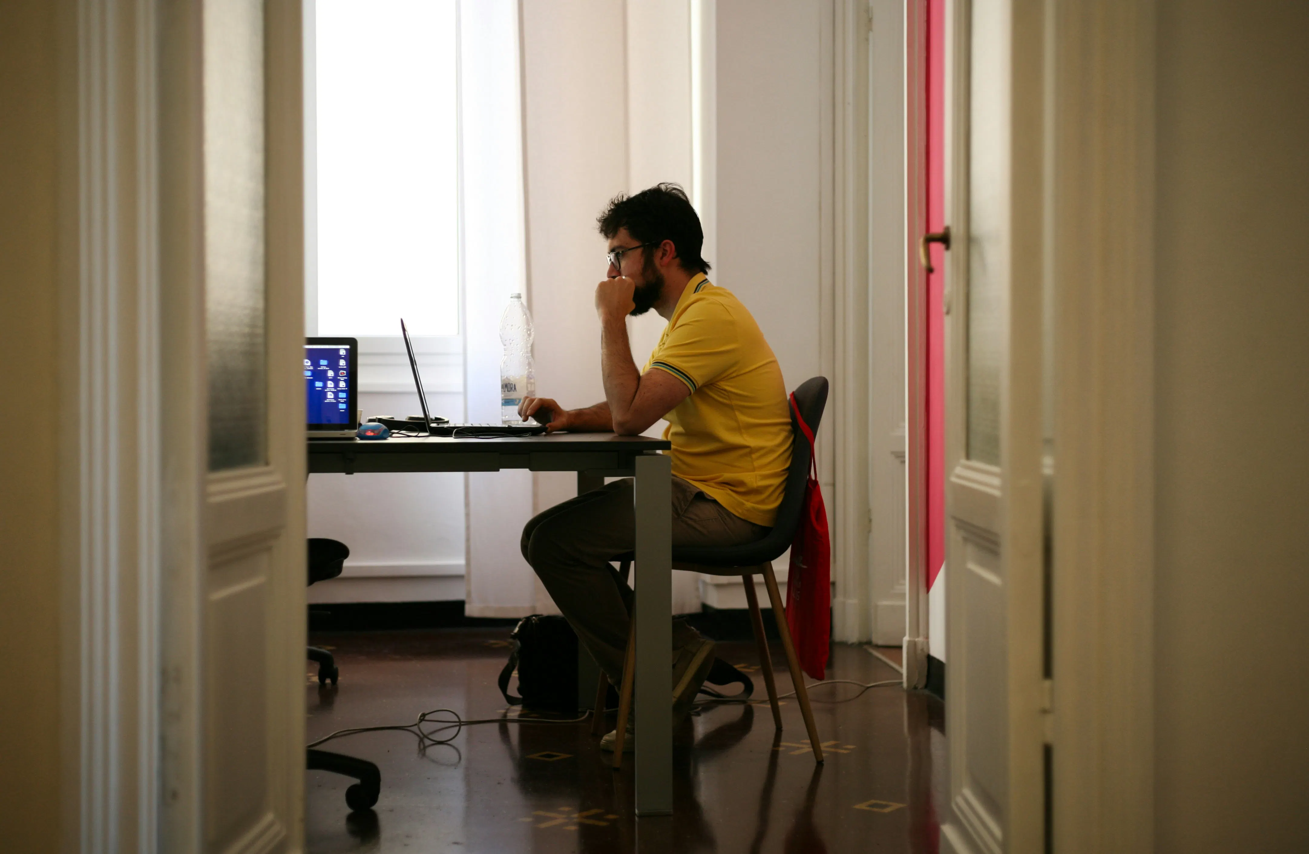 Hôte Airbnb travaillant sur son ordinateur dans un bureau lumineux.