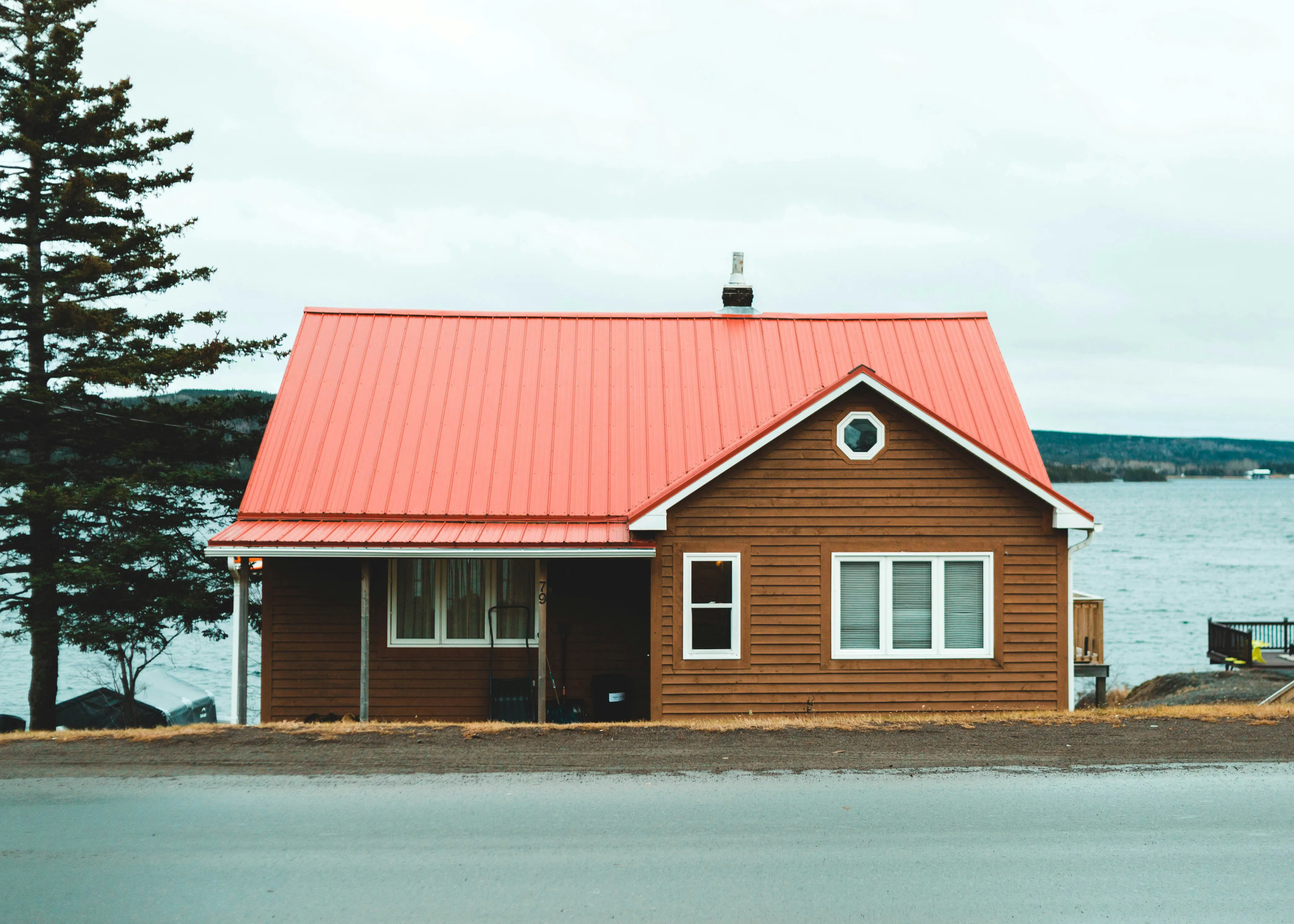 Waterfront cabin with a red roof, ideal for short-term rental seekers looking for lakeside stays in Canada.