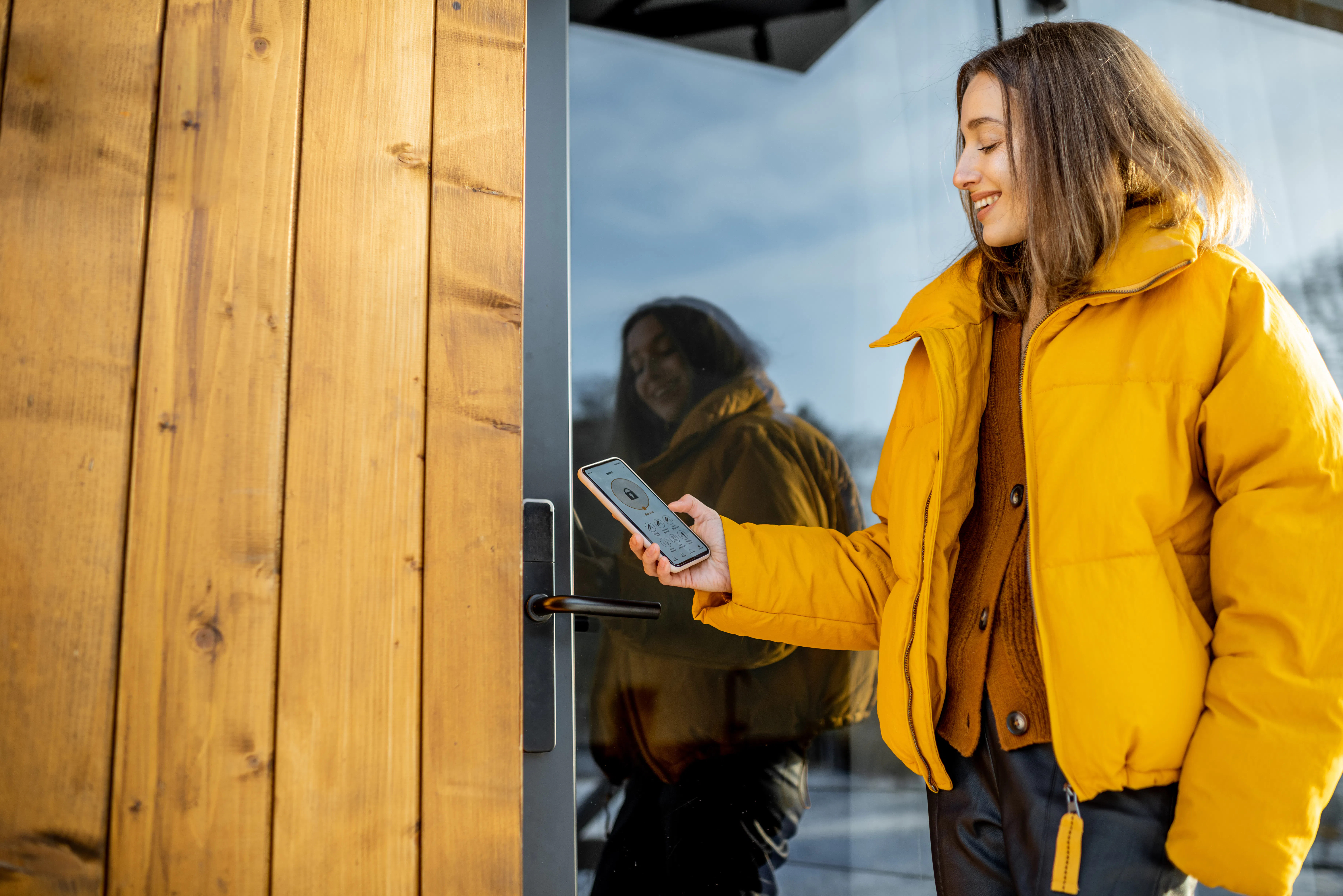 Woman locking smartlock on the entrance door using a smart phone.