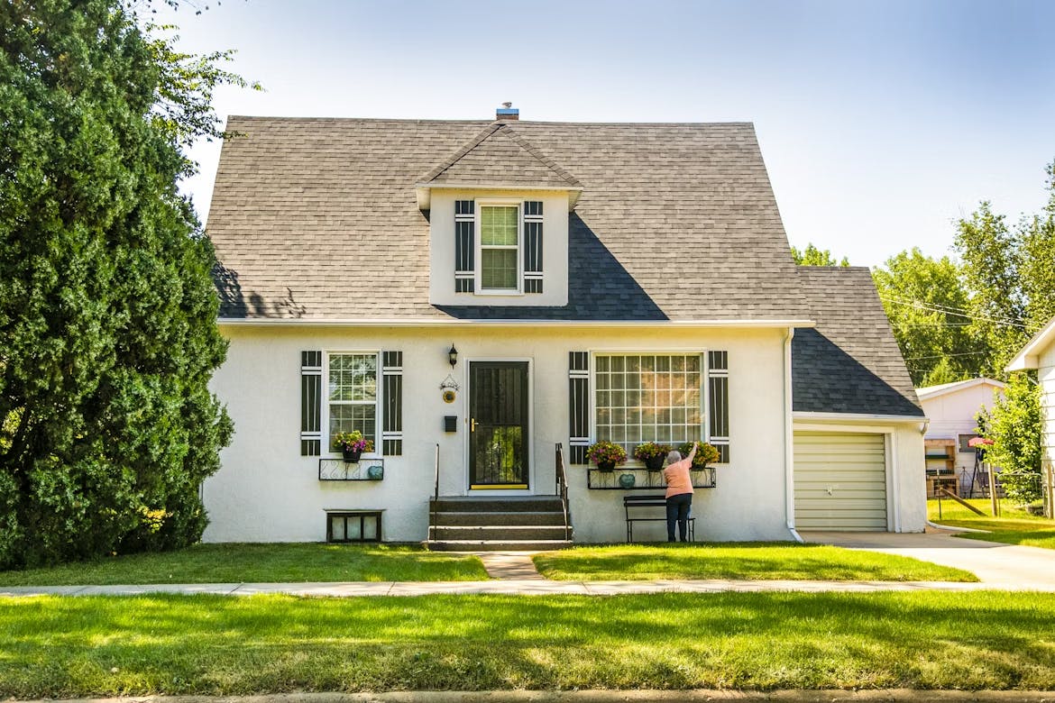 White cottage with woman tending front yard