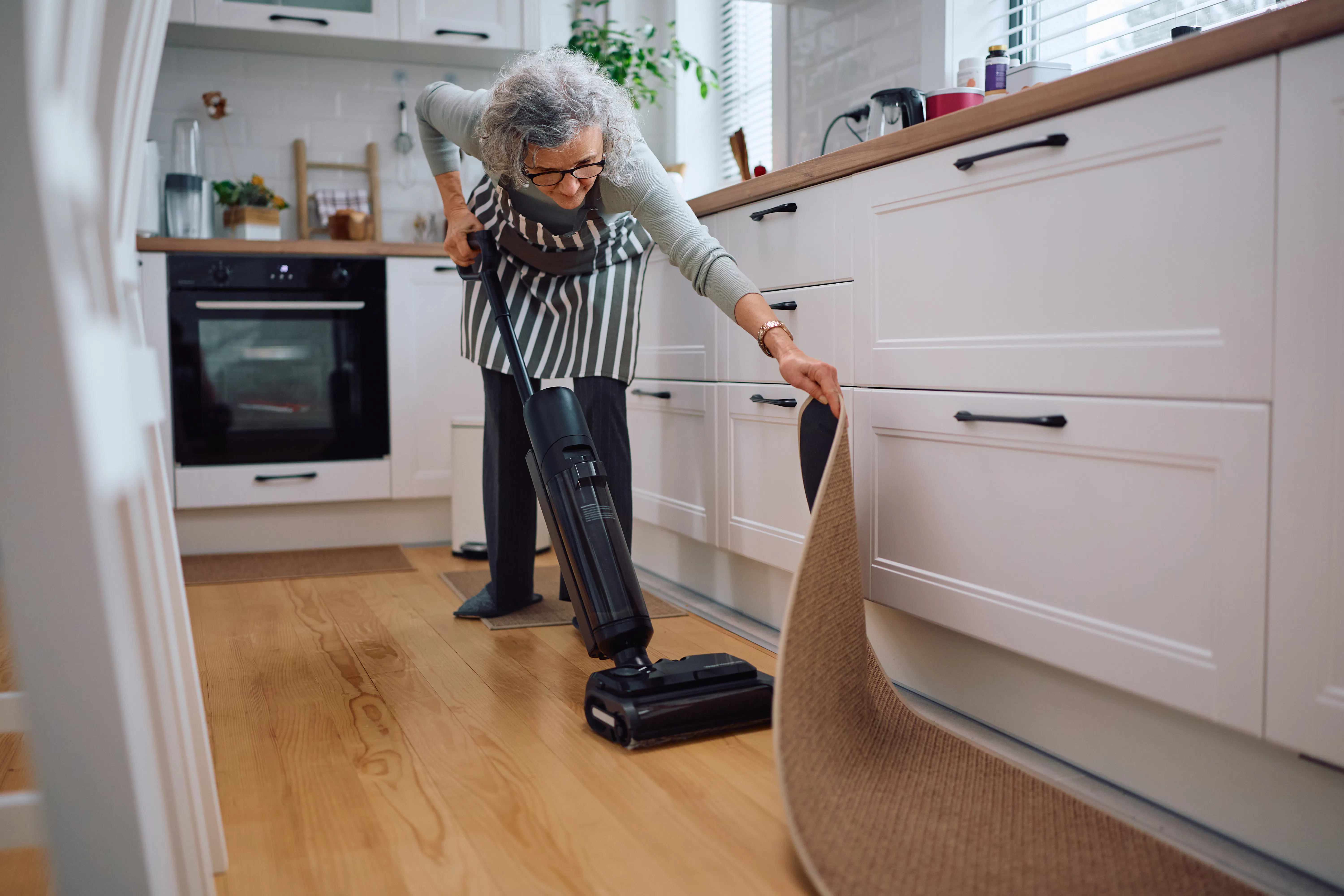 Woman vacuuming kitchen