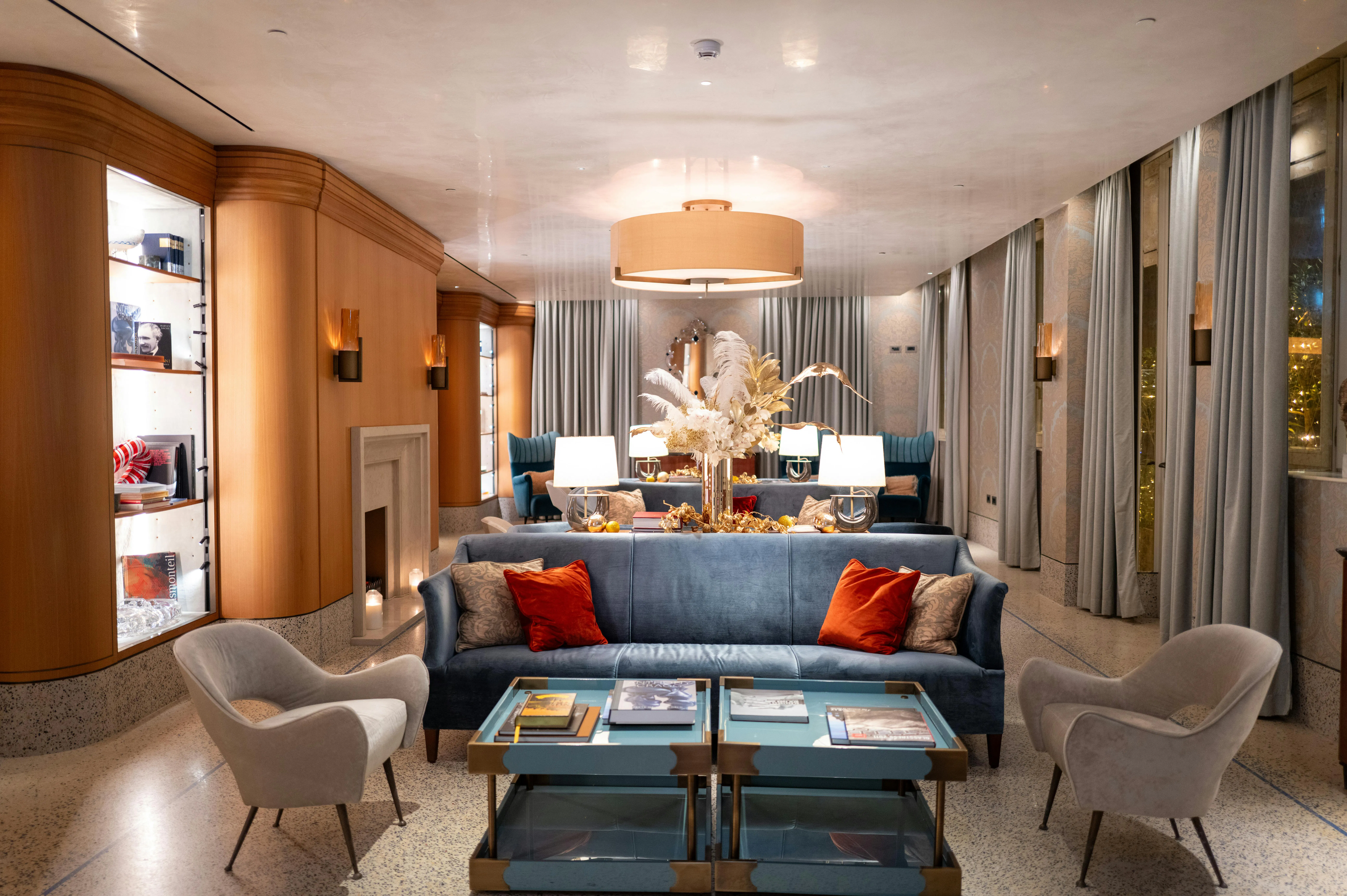 Un luxueux salon d'hôtel avec un canapé bleu, deux fauteuils, et une table basse décorée de livres.
