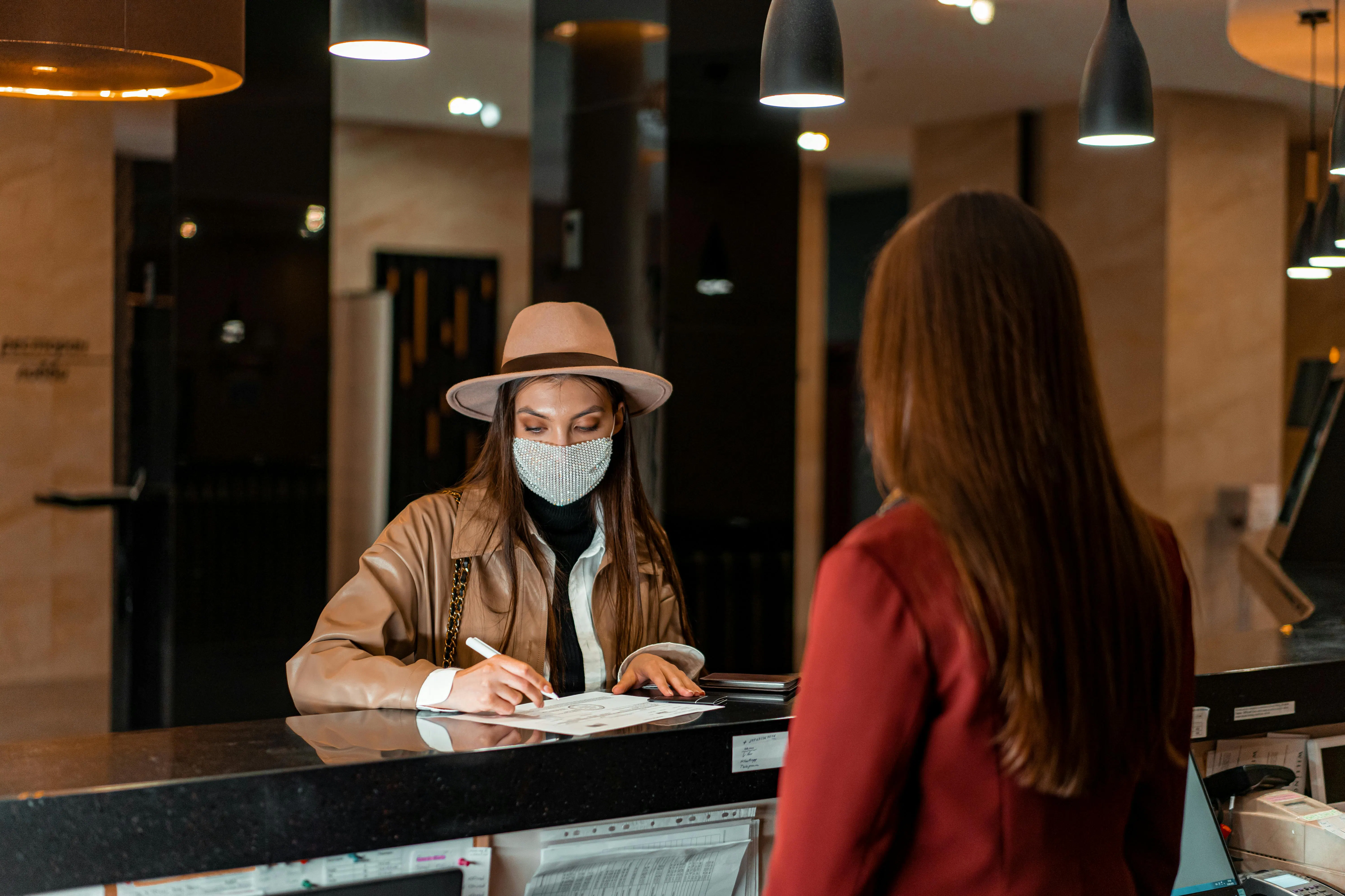 Deux femmes au comptoir d'un hôtel, l'une en train de signer des documents d'annulation